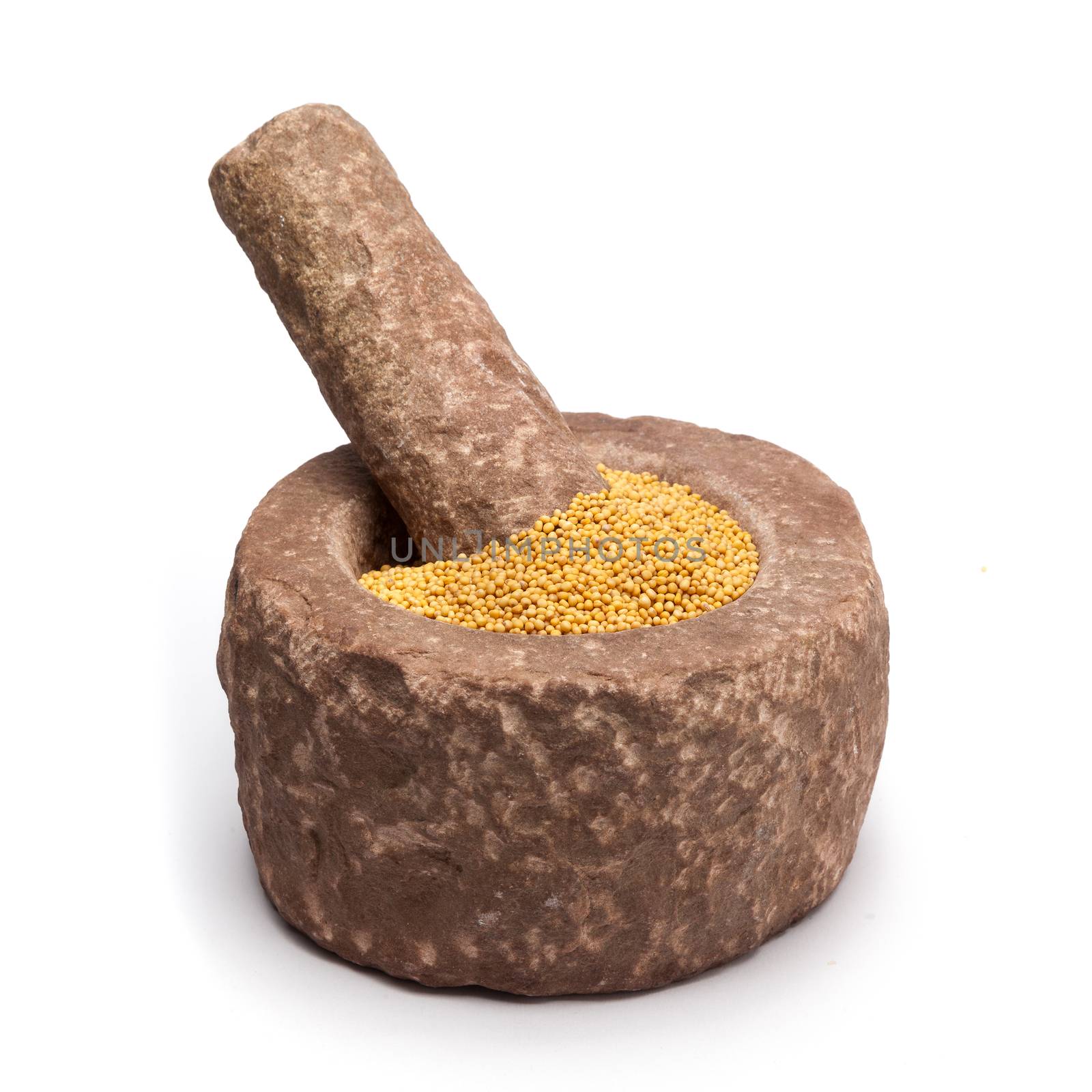 Organic yellow mustard (Brassica alba) in mortar with pestle, isolated on white background.