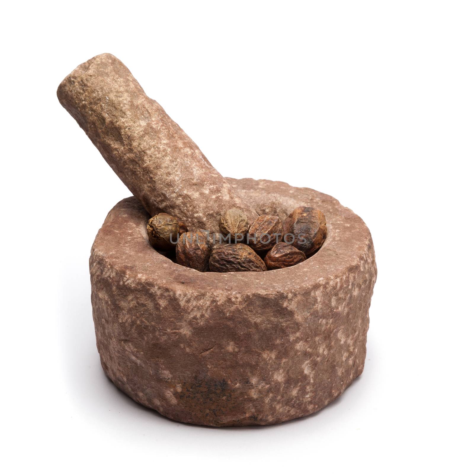 Organic Inknut or Harr (Terminalia chebula) in mortar with pestle, isolated on white background.