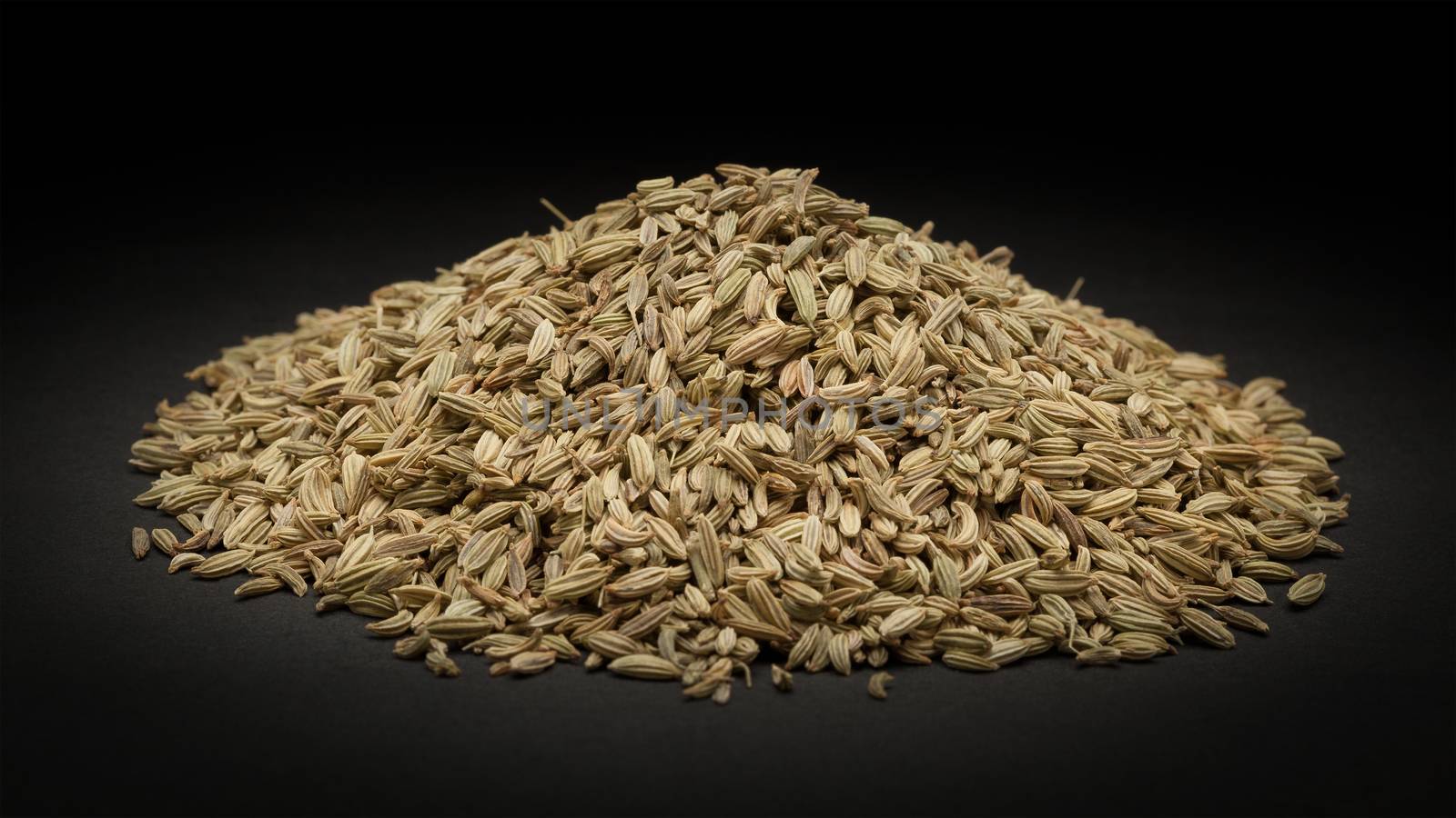 Pile of Organic Fennel seed (Foeniculum Vulgare) on dark background.