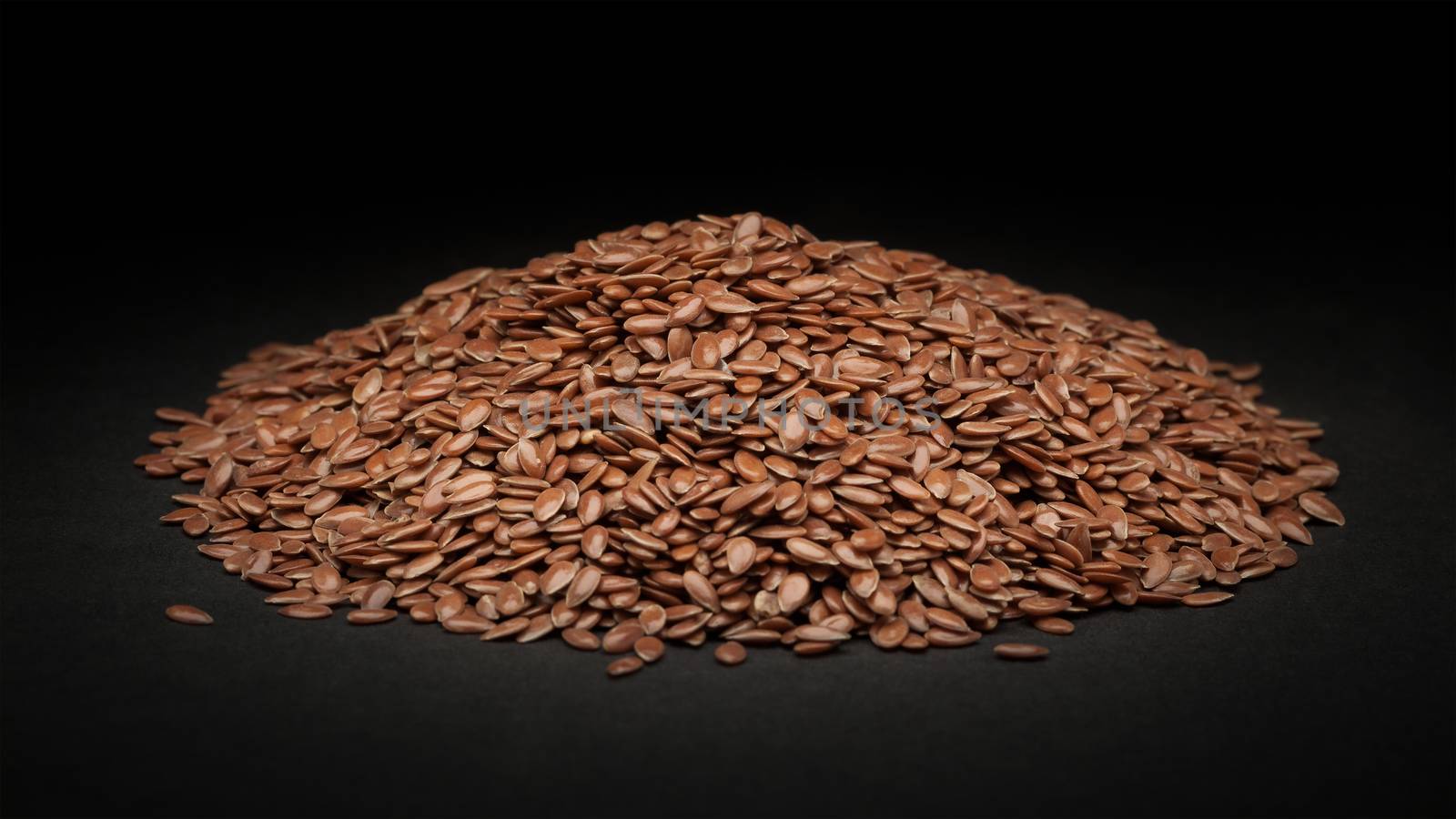 Pile of Organic Linseed or Flaxseed (Linum usitatissimum) on dark background.