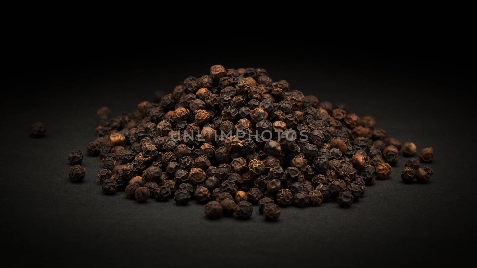 Pile of Organic Black pepper (Piper nigrum) on dark background.
