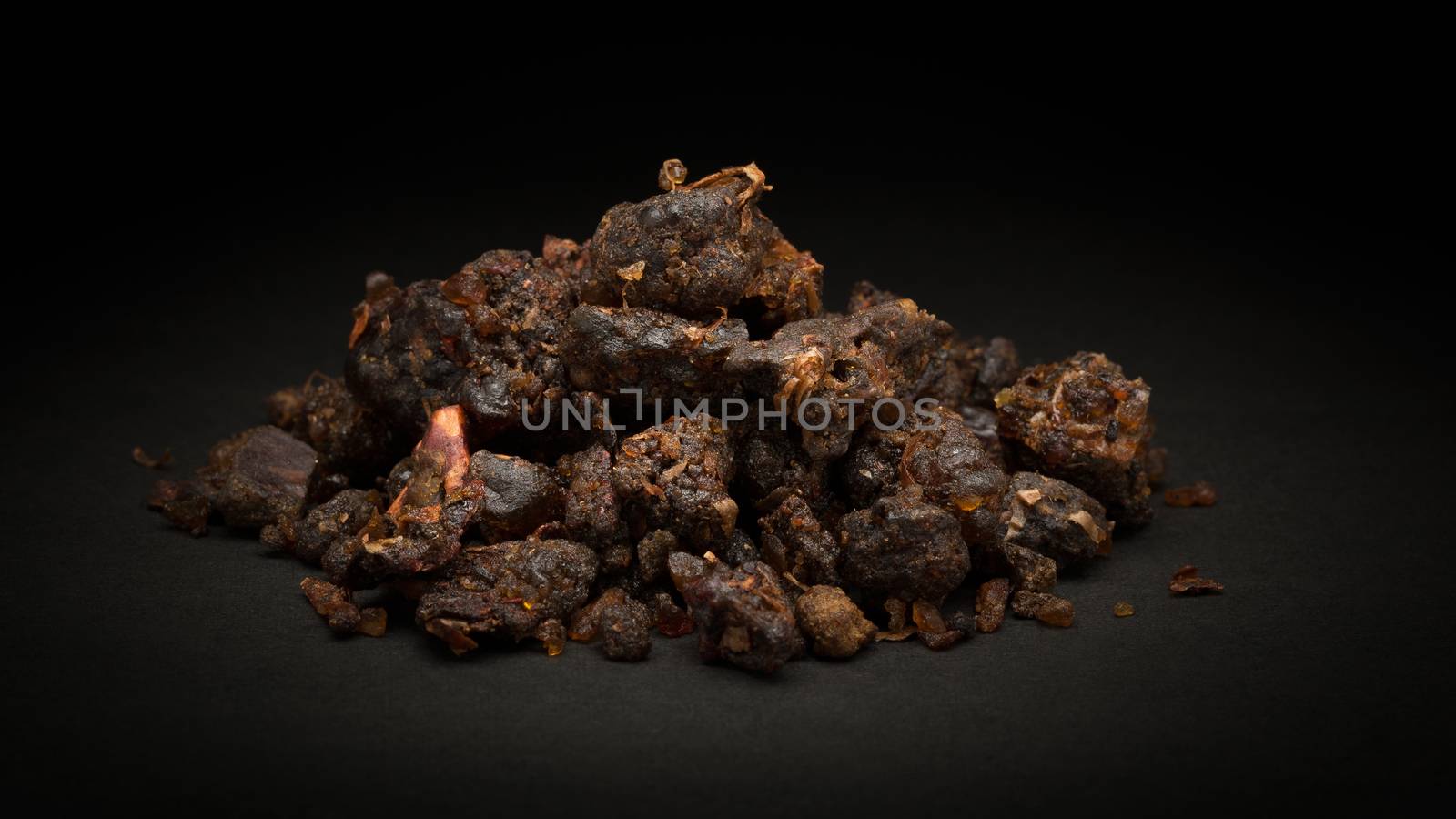 Pile of Organic Indian bdellium or Guggul resin (Commiphora wightii) on dark background.