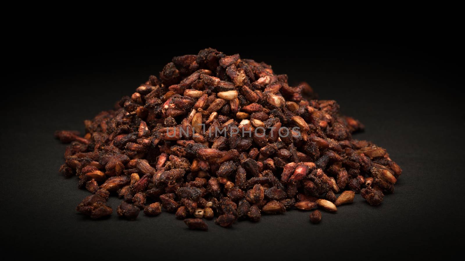 Pile of Organic Dried Pomegranate seeds (Punica granatum) on dark background.
