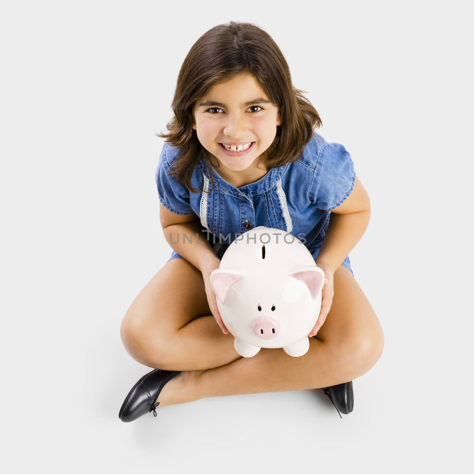 Young girl sitting on floor and holding a piggybank