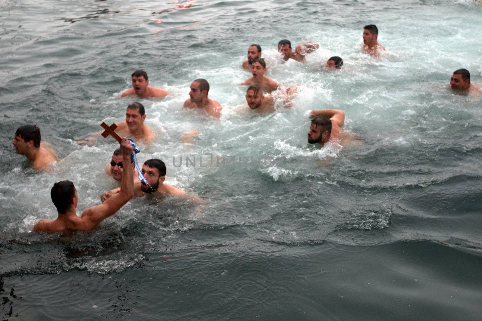 GREECE, Thessaloniki : A swimmer holds in the air a wooden cross he retrieved from the sea, during the blessing of the water ceremony marking the Orthodox Epiphany Day, in Greece's northern port of Thessaloniki on January 6, 2016.Similar celebrations for the Epiphany Day are held across the country and region on river banks, seafronts and lakes.