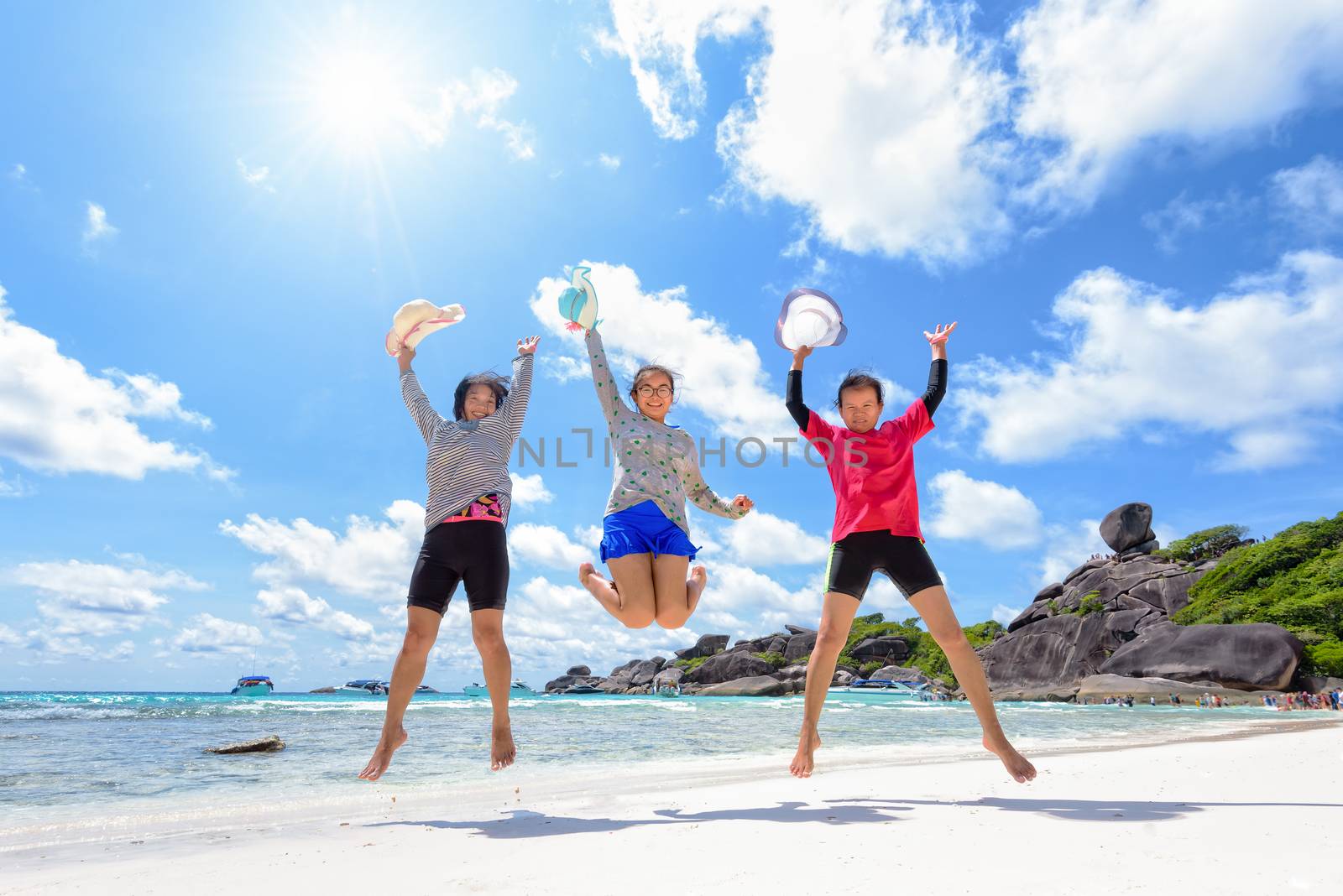 Tourist women three generation family jumping for happy on beach near the sea under the sky clouds and sun of summer at Similan Island in Mu Ko Similan National Park, Phang Nga province, Thailand