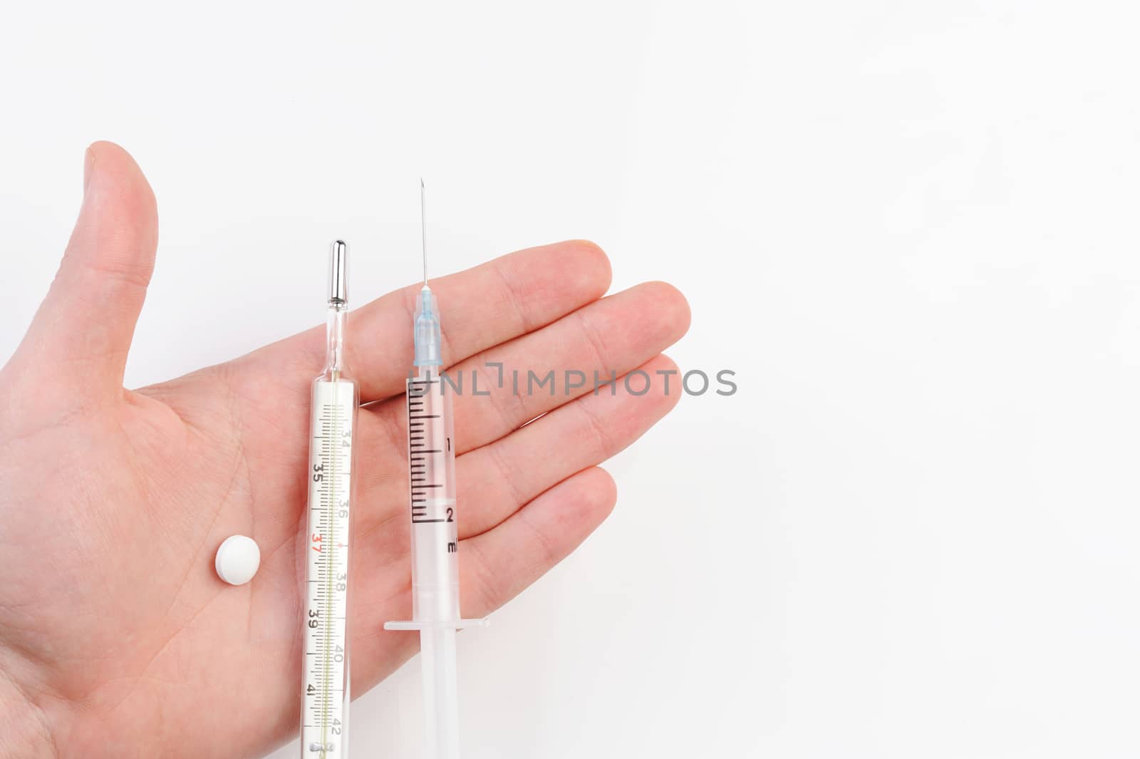 medical set in hand of pill, syringe and thermometer on hand