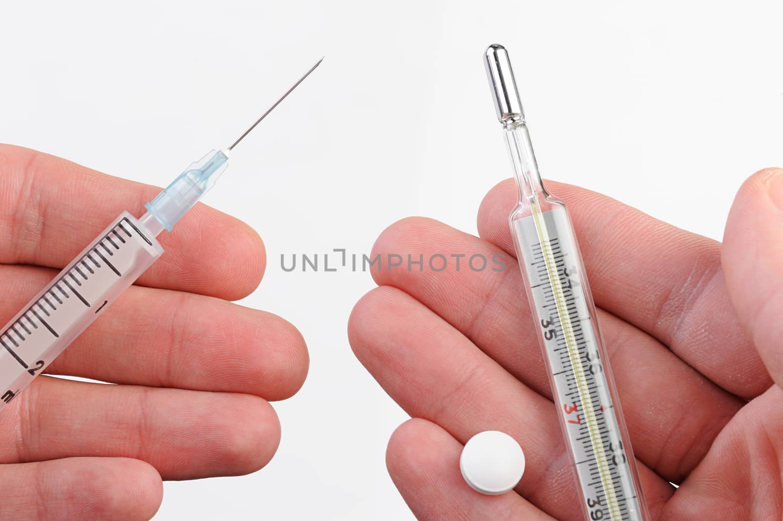 close up of thermometer, syringe, and pills on hands on white