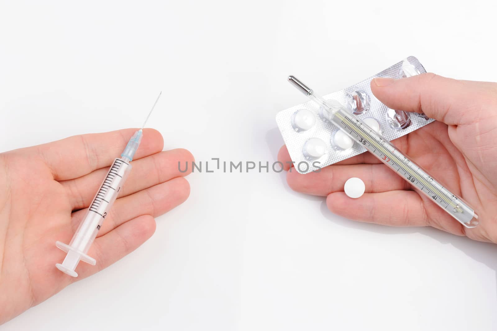  thermometer, syringe, and pills on hands on white