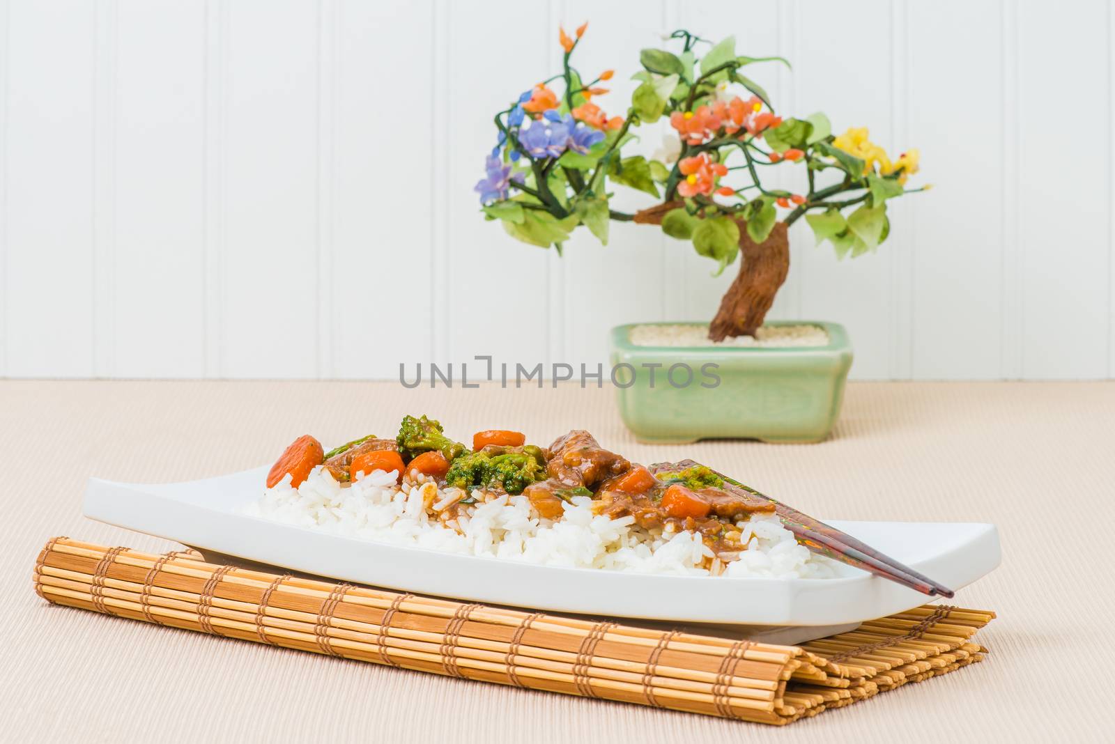 Plate of oriental beef and broccoli served on a bed of white rice.