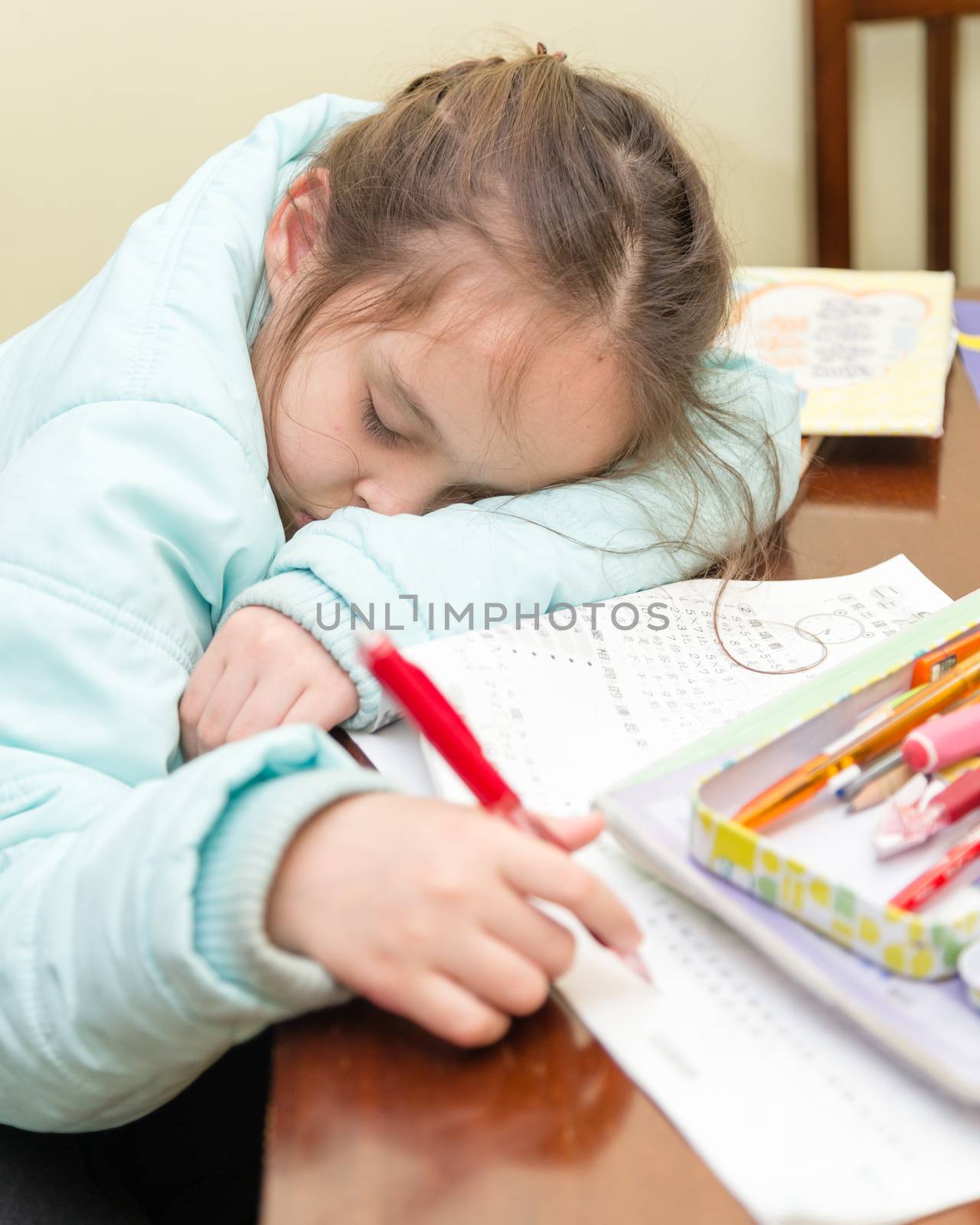 Young schoolgirl falling asleep while doing her homwork