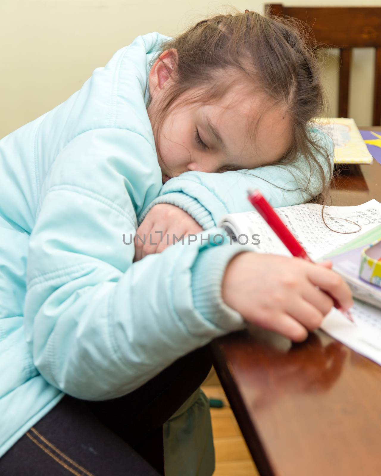 Young schoolgirl falling asleep while doing her homwork