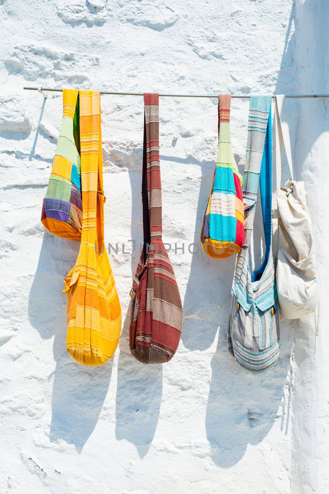 Hand made coloured bags hanging on white wall