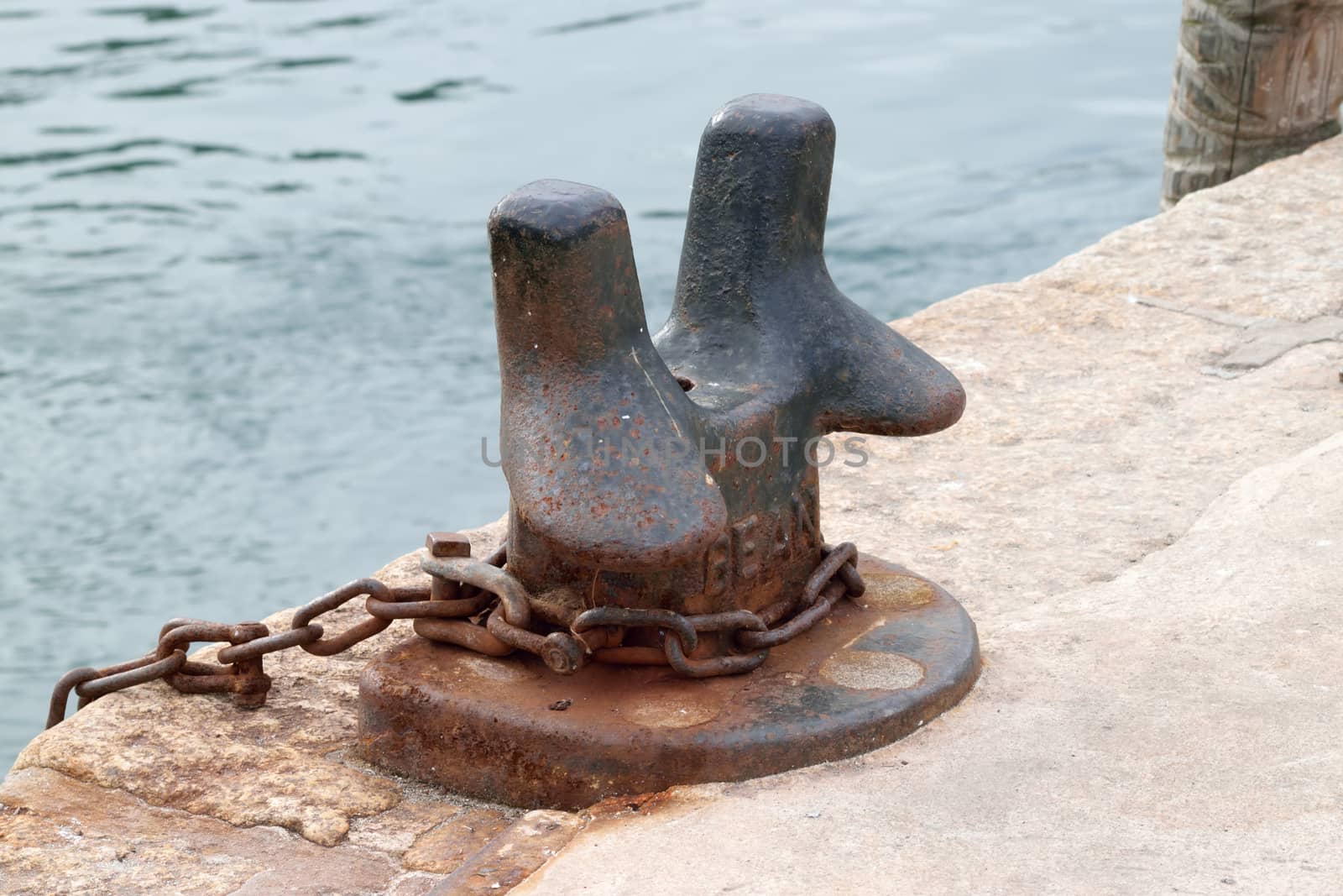 Old and rusted.

Iron bollard and chain in the port of Looe, Cornwall, used to tying up of boats to harbour.