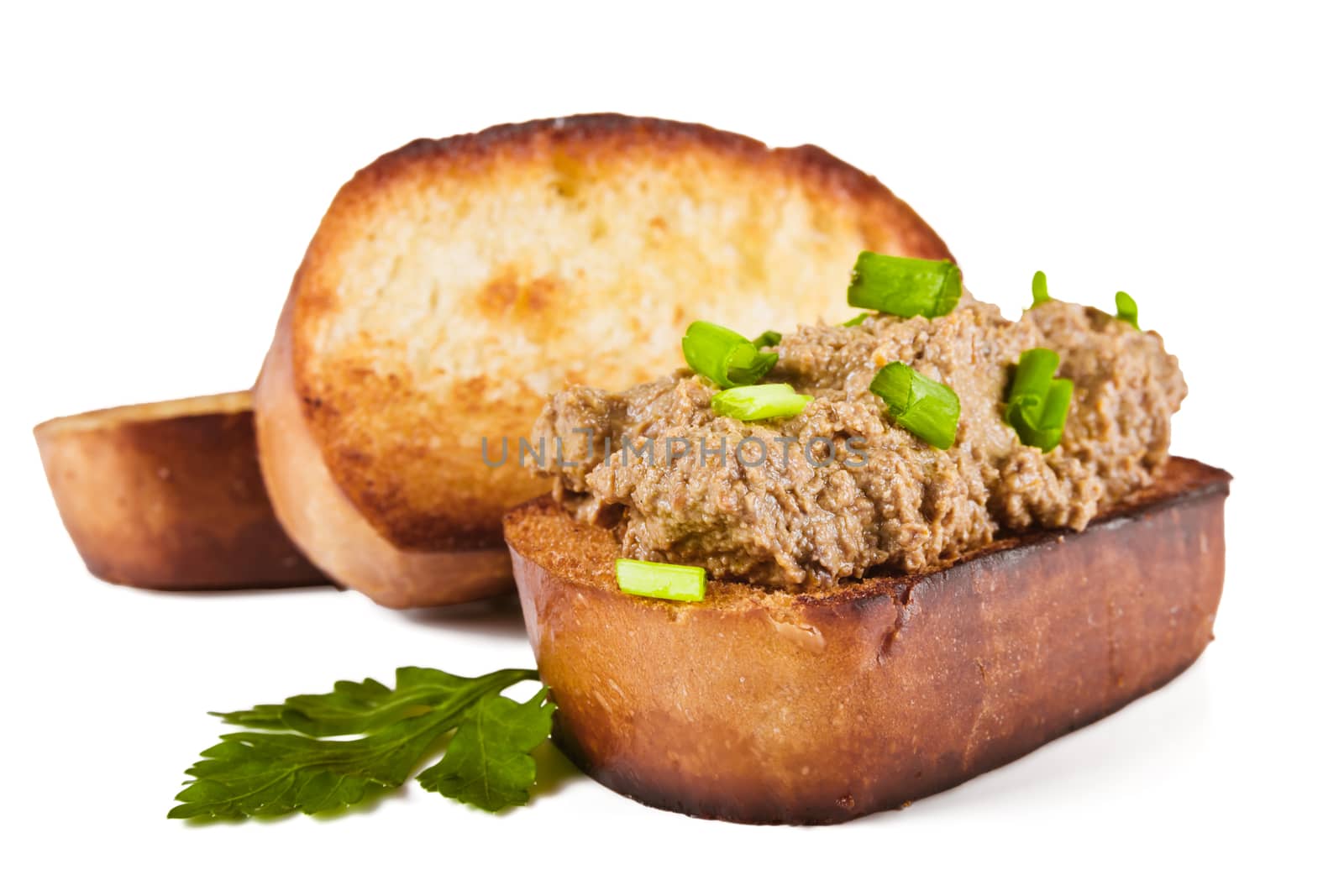 Fried bread with liver pate, green onions and parsley leaves on a white background