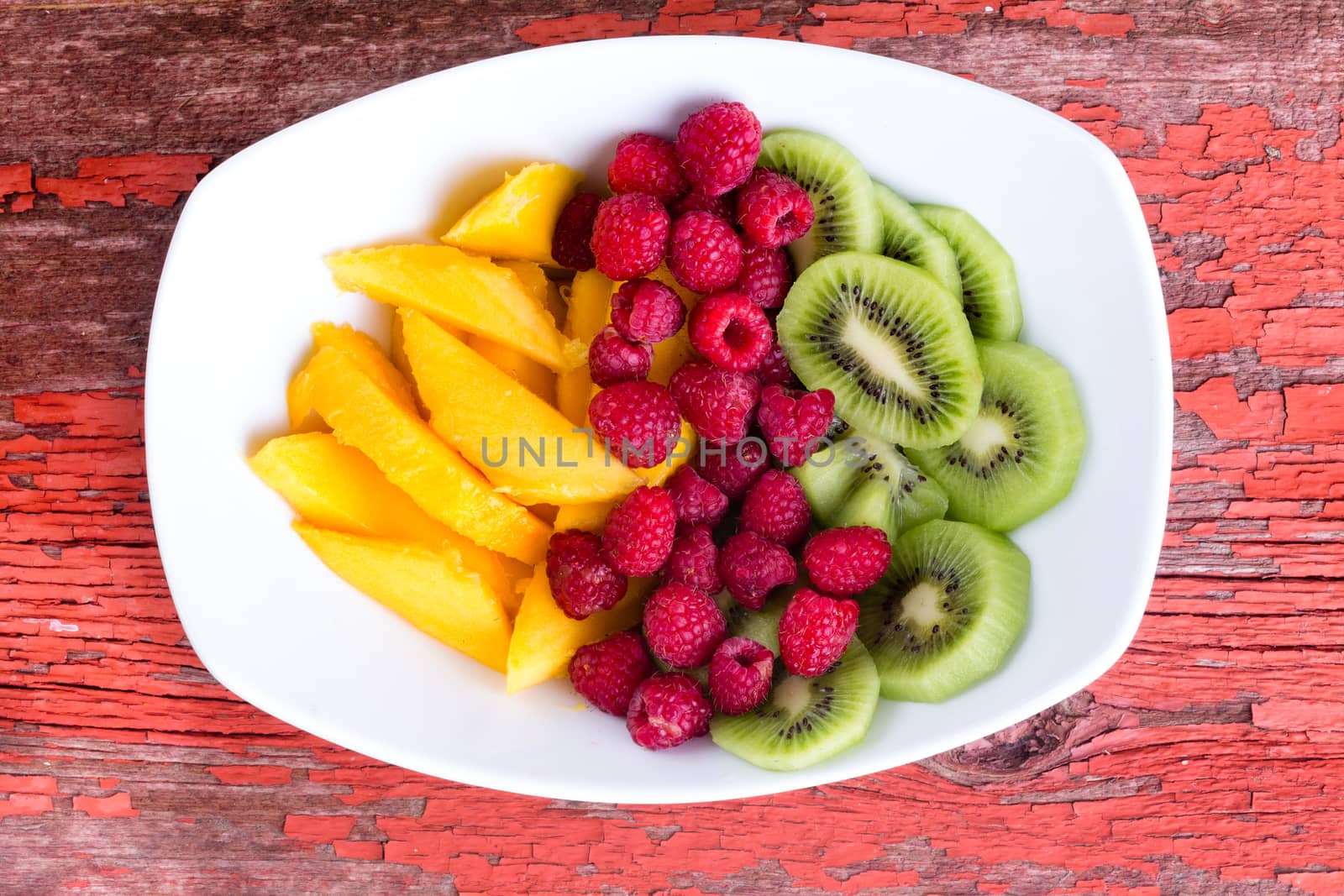 Top view of various fruit in plate on old wood table