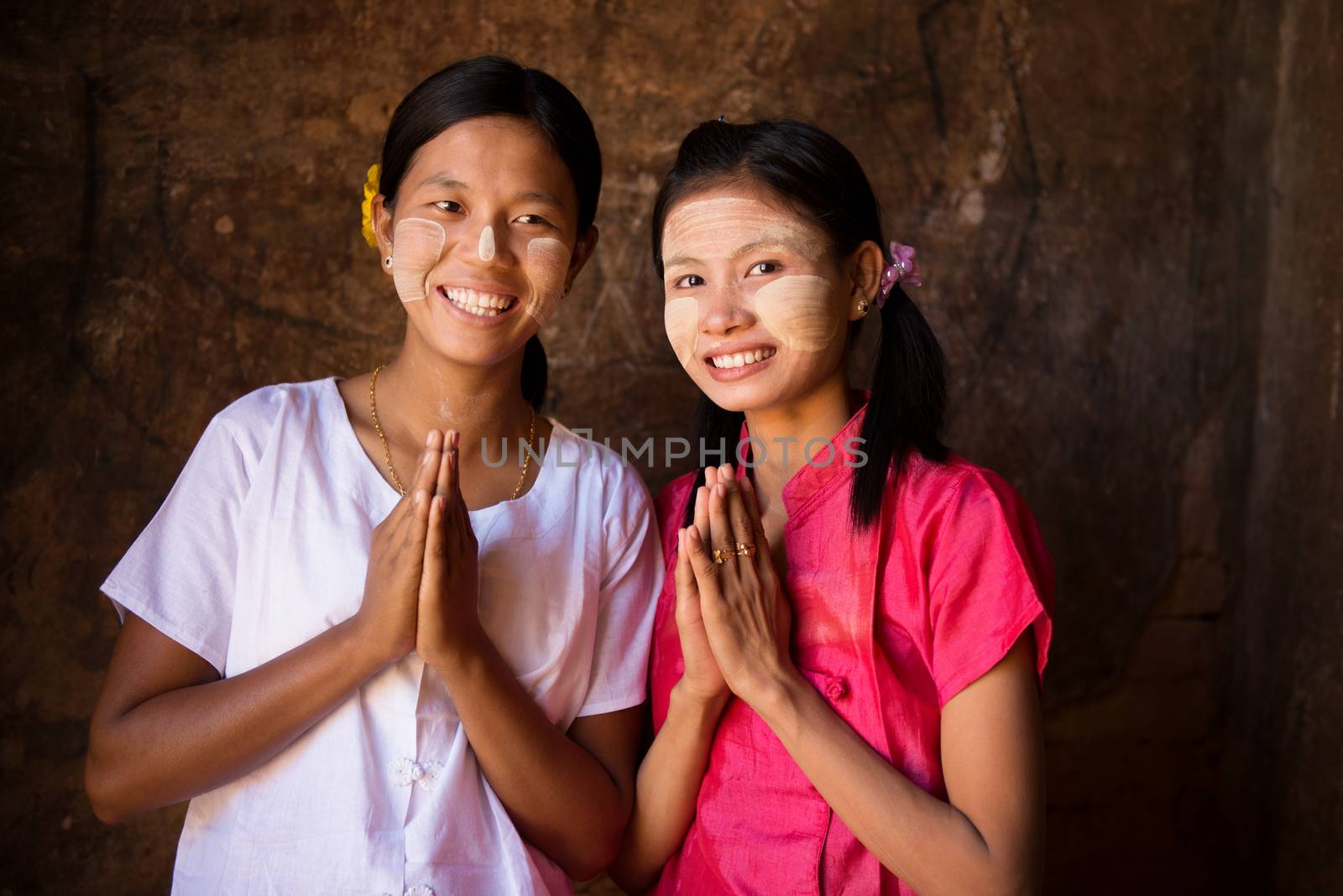 Two young Myanmar women in a traditional welcoming gesture.