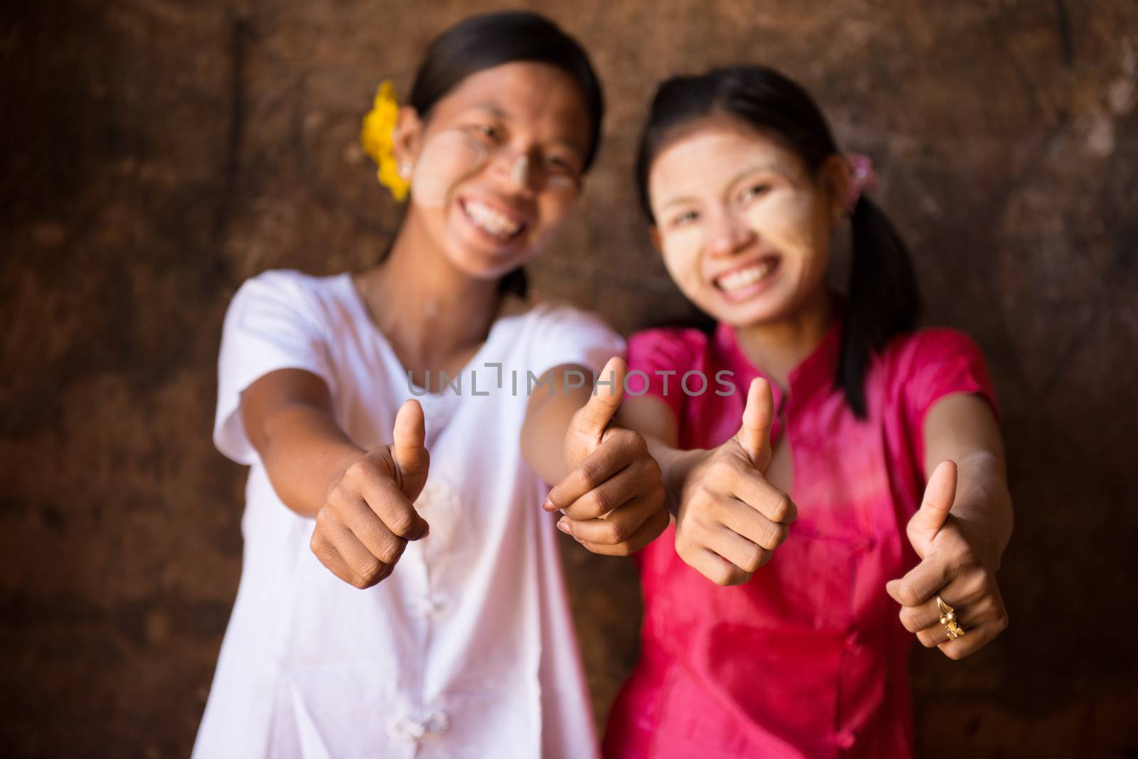 Portrait of two beautiful Myanmar girls smiling and giving thumb up.