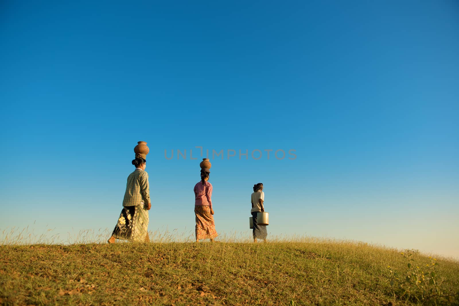 Group of Asian traditional farmers carrying clay pots on head going back home, Bagan, Myanmar