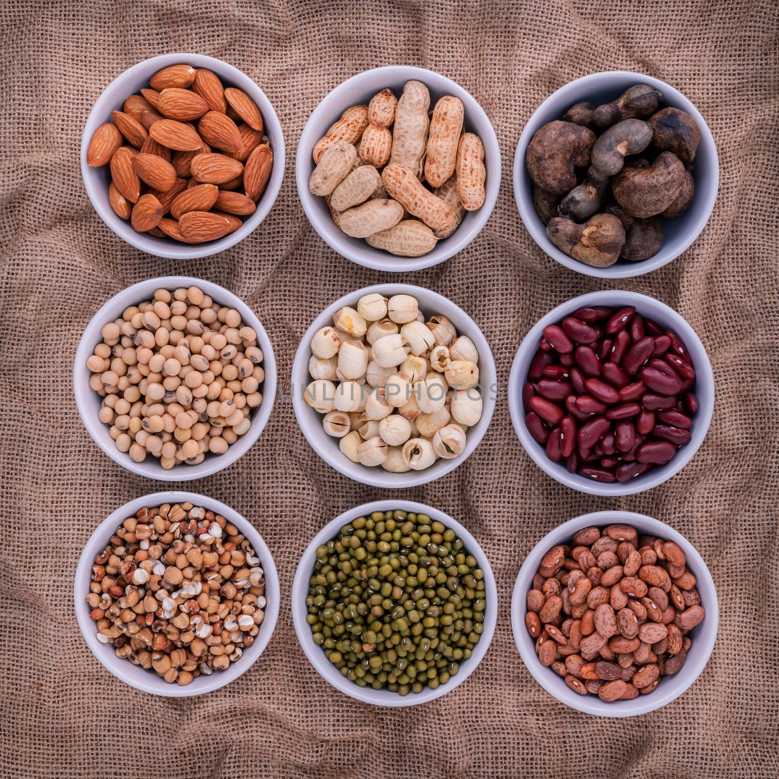 Mixed beans , lentils and nuts in the white bowl on brown cloth  by kerdkanno