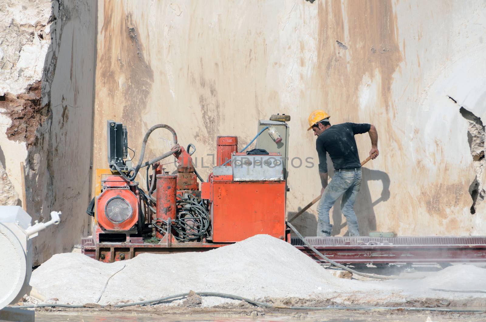 Industrial marble quarry, with cut blocks and workers and machines at work.