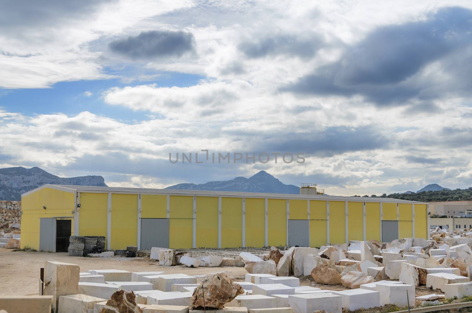 Industrial marble quarry, with cut blocks and workers and machines bulldozer at work.