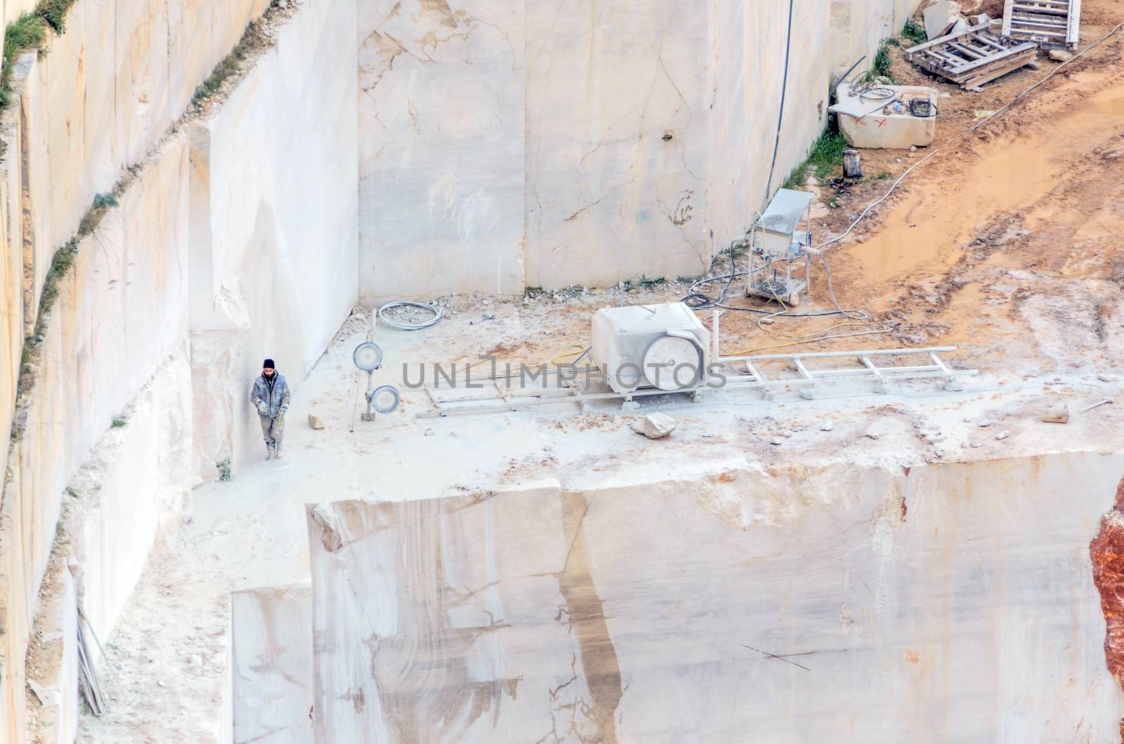 Industrial marble quarry, with cut blocks and workers and machines bulldozer at work.