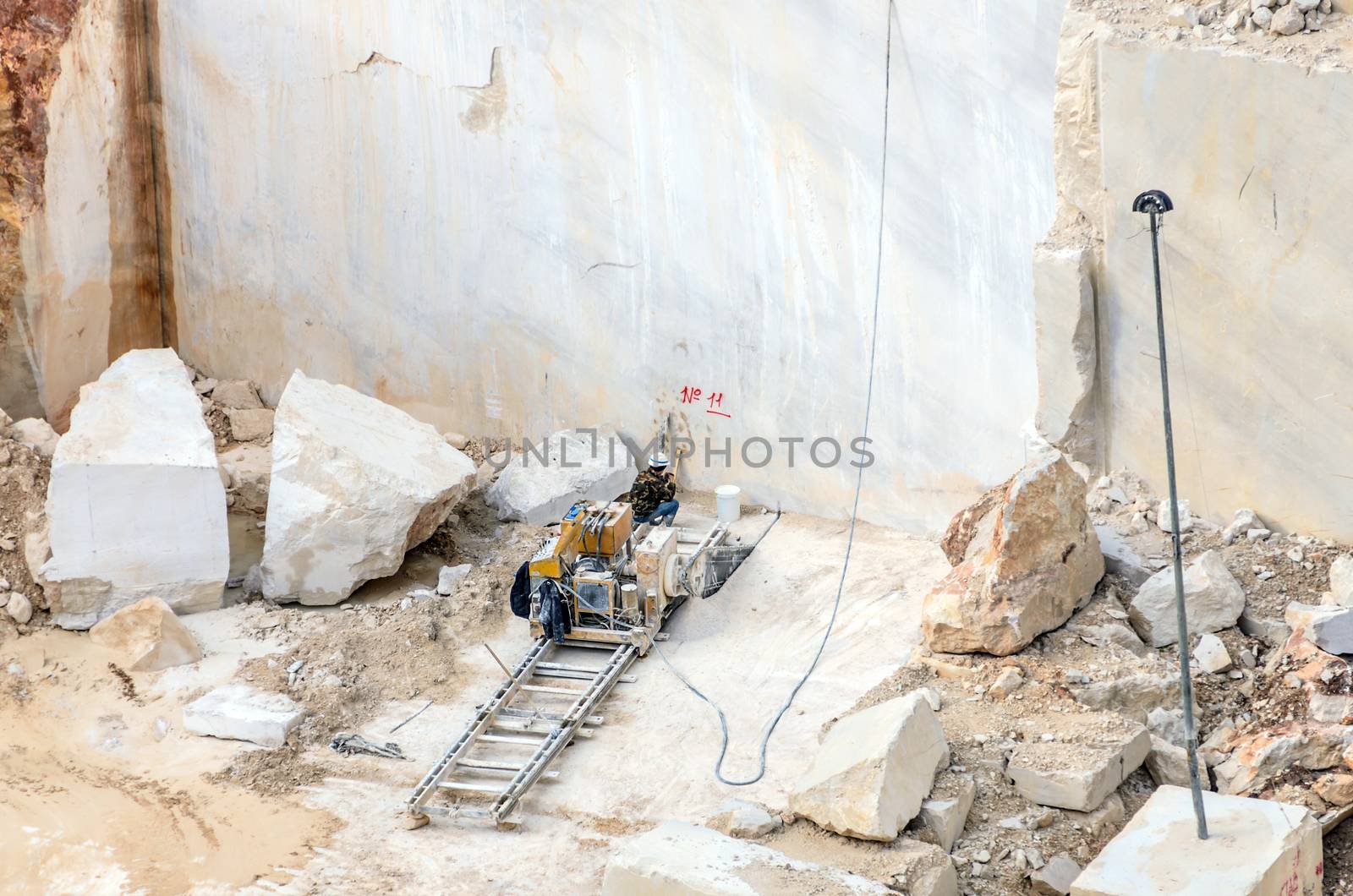 Industrial marble quarry, with cut blocks and workers and machines bulldozer at work.