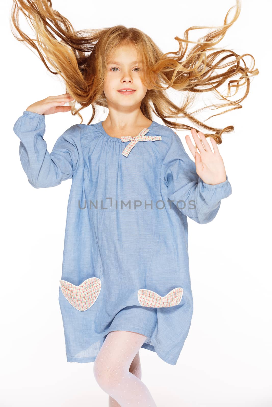 Jumping little girl in a blue dress with flying curls