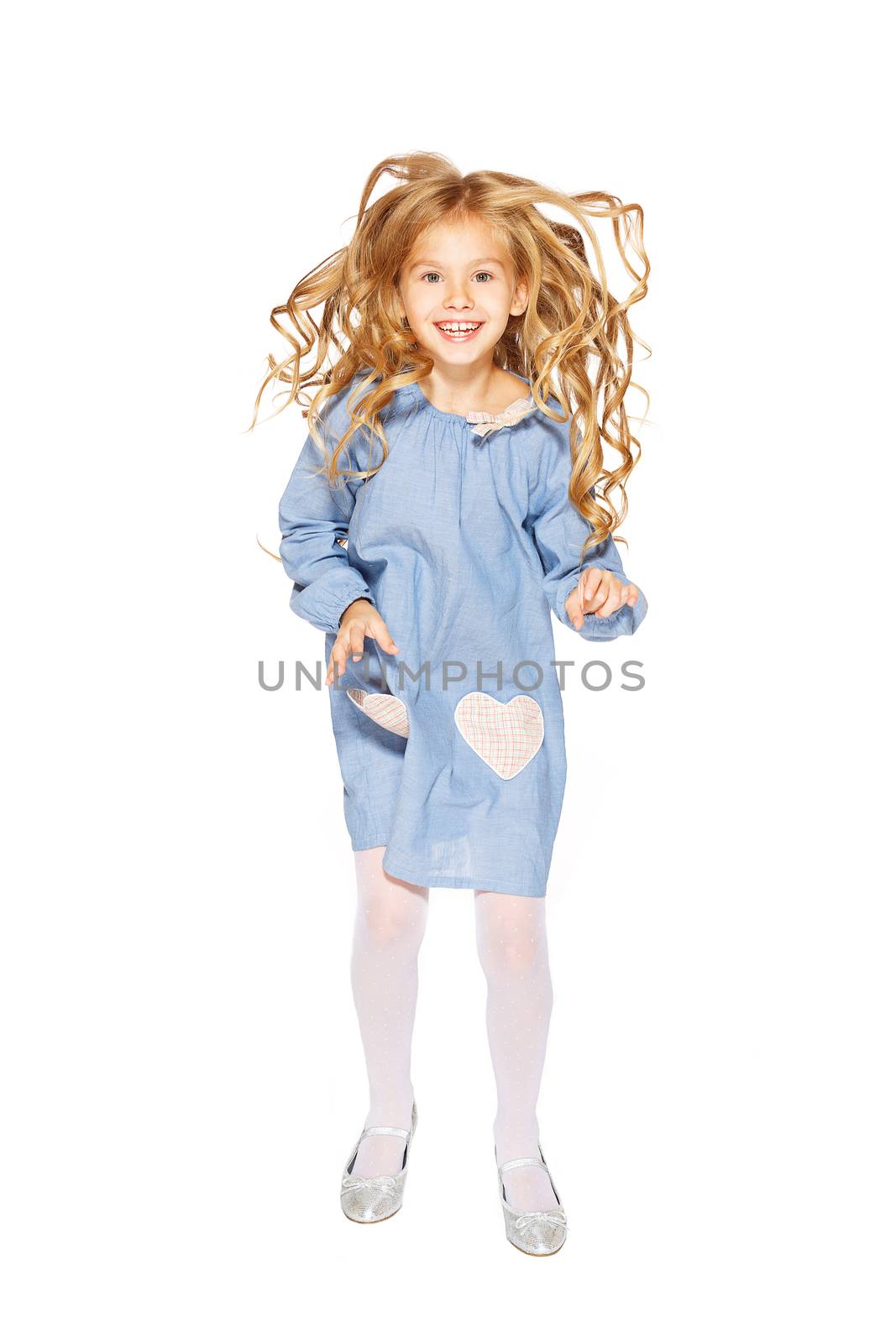 Jumping little girl in a blue dress with flying curls