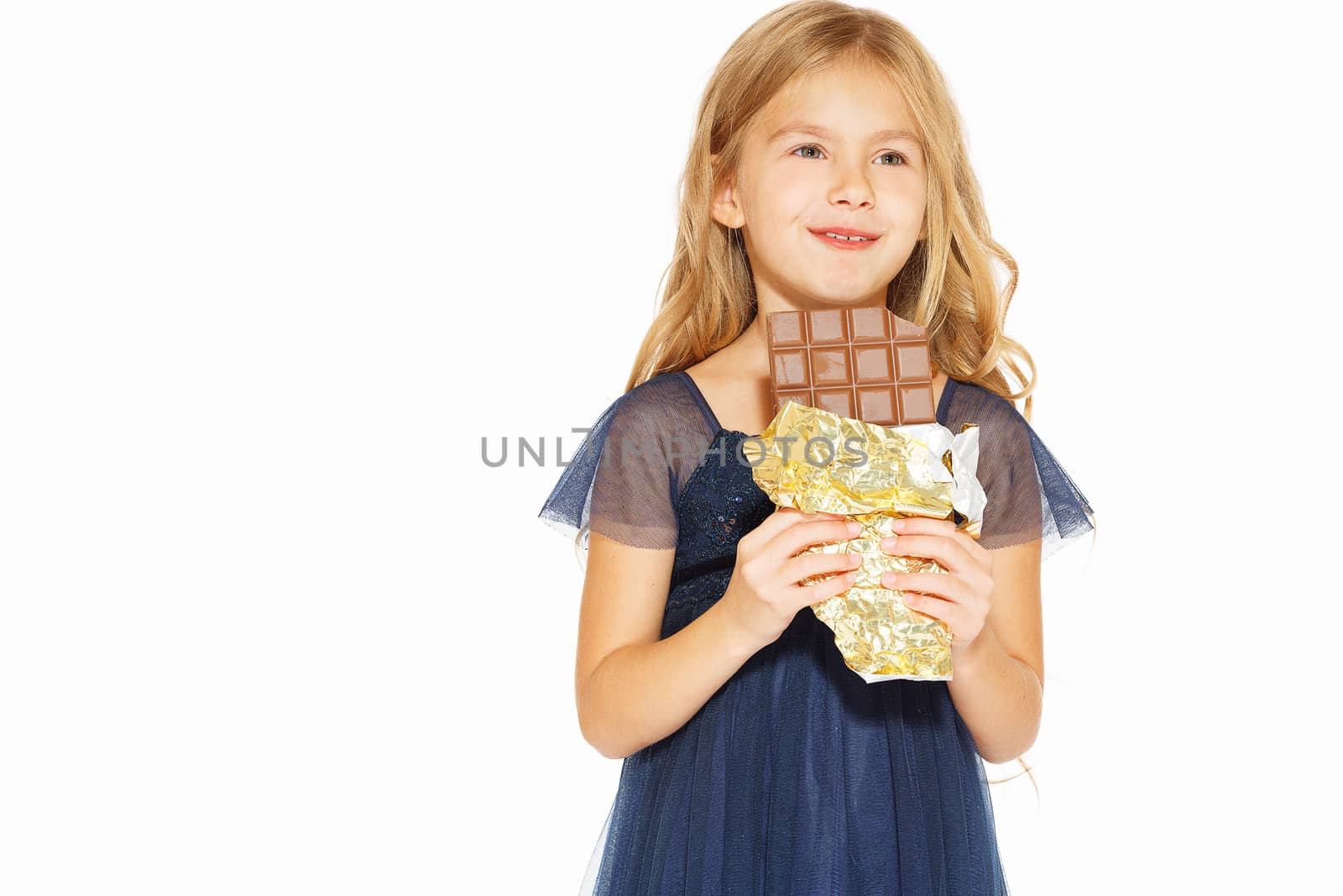 Beautiful blonde girl in a blue dress with curls eating a chocolate