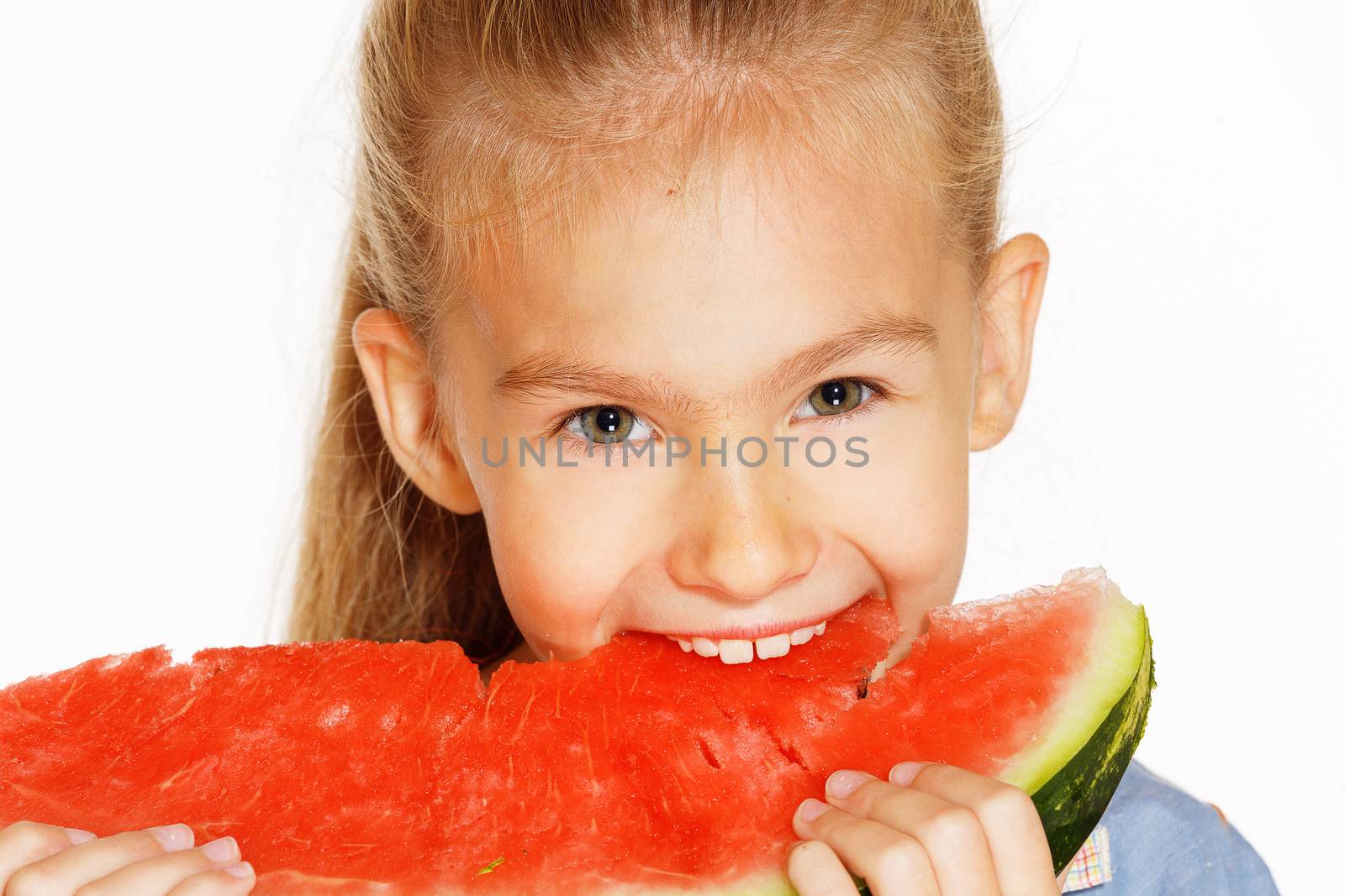 Cute girl in a blue dress eating red juicy watermelon