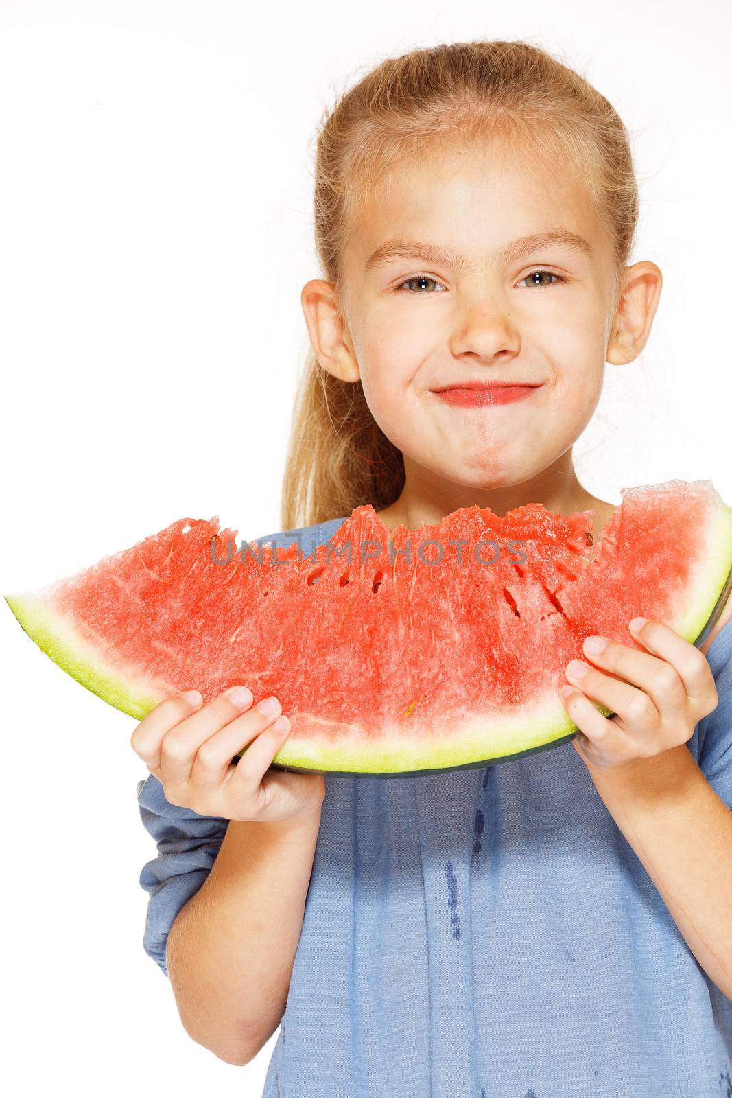 Cute girl in a blue dress eating red juicy watermelon