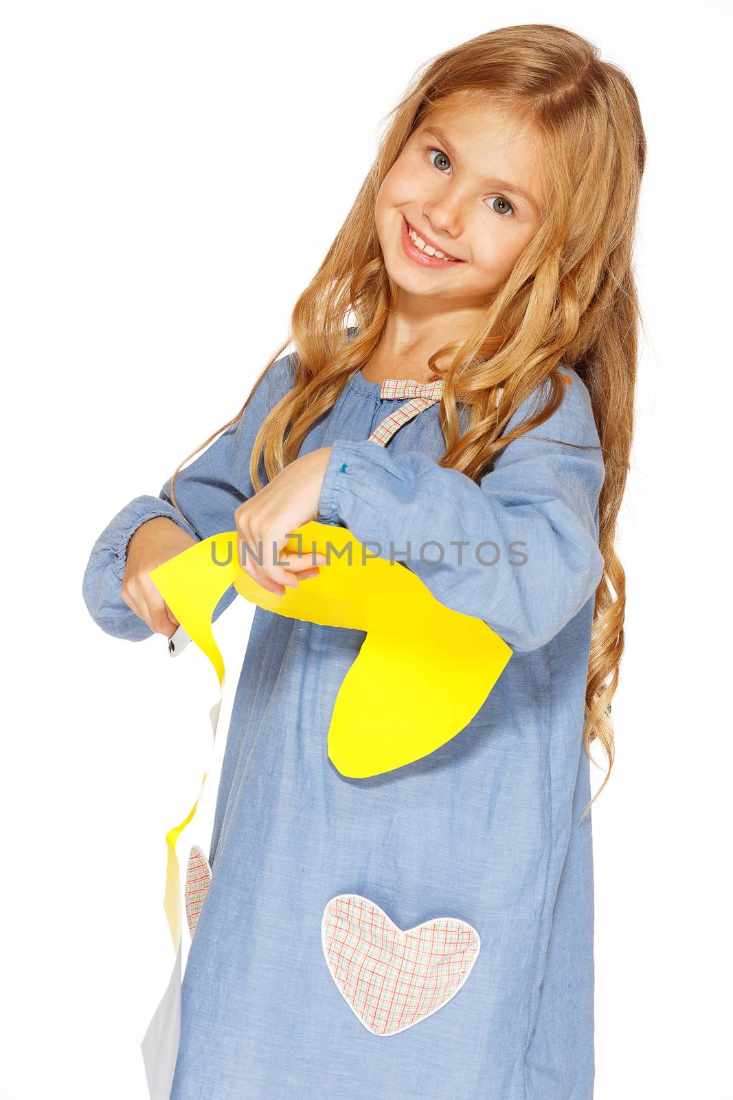 Little cute girl making handmade yellow hearts