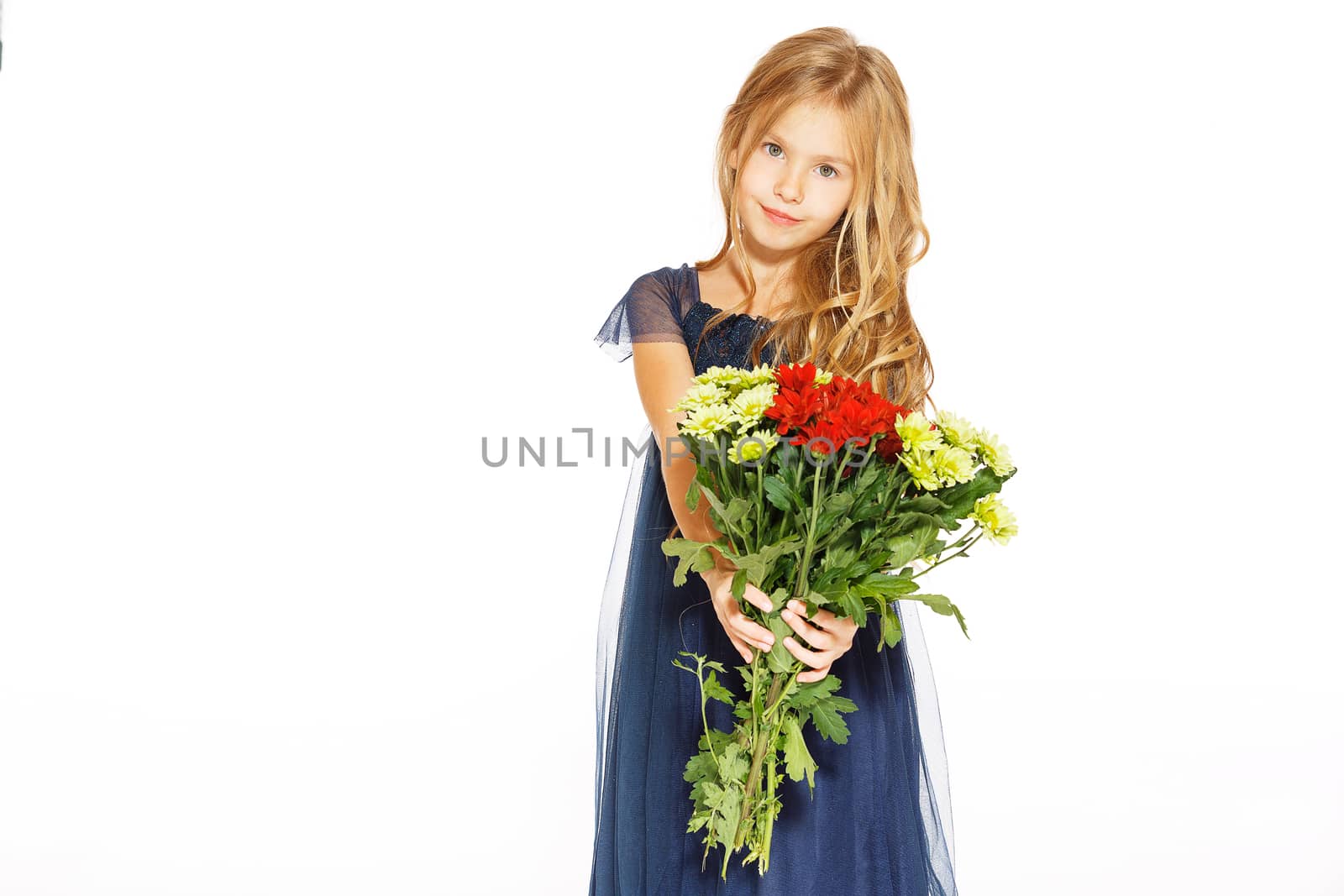 Charming little girl with curly hair in a blue dress with a bouquet of flowers