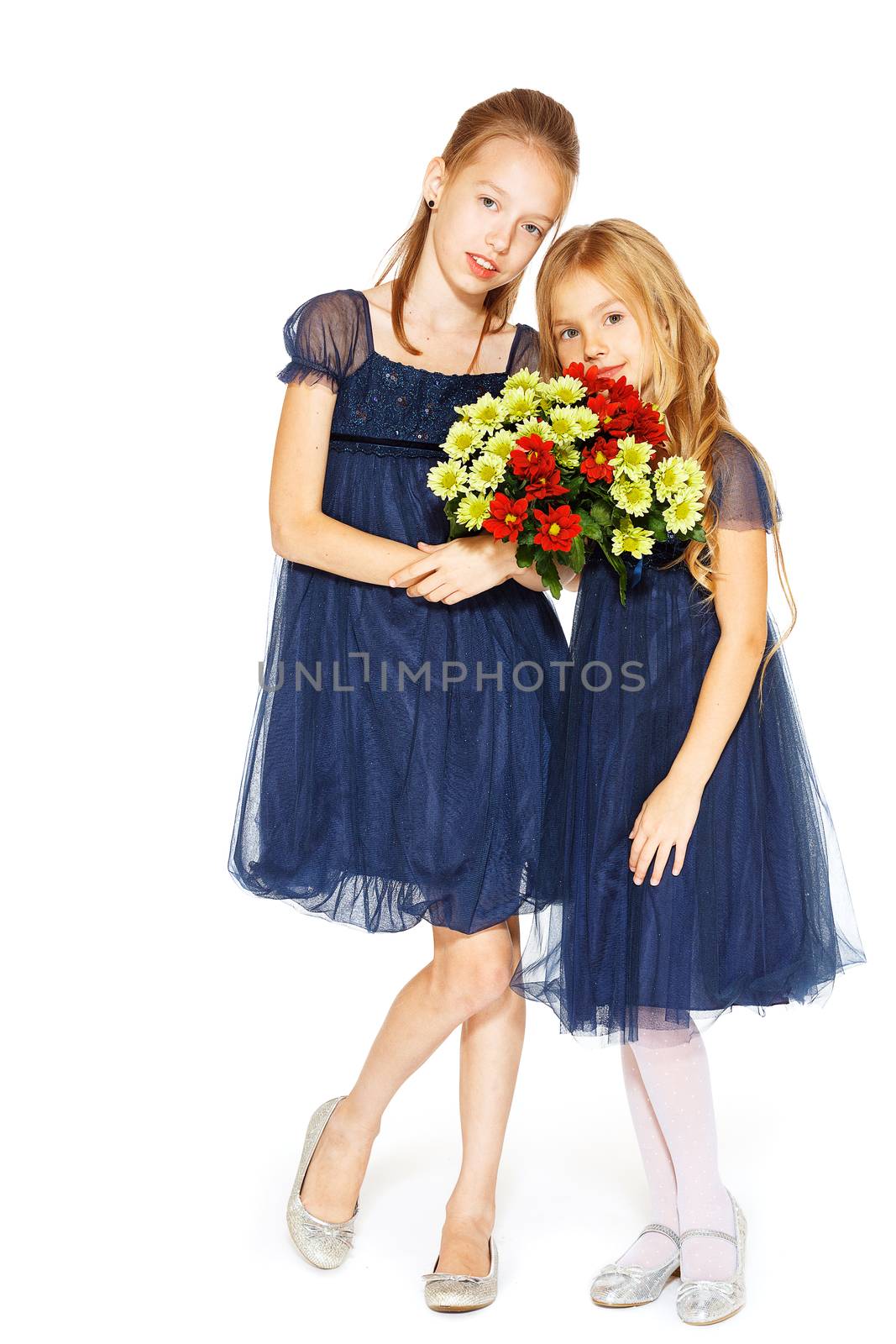 Two charming little girls in a blue dresses with a bouquet of flowers