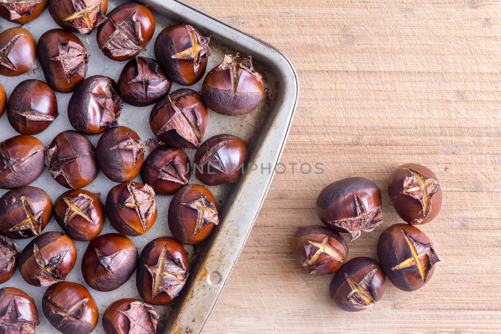 Tray of roasted chestnuts on table by coskun