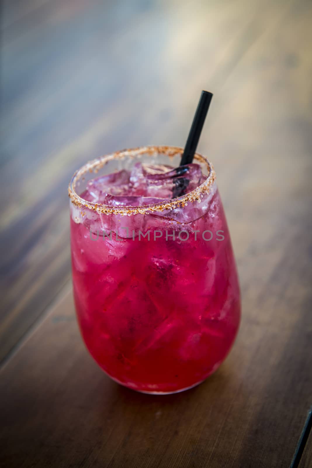 Image of a bright red cocktail on wood table