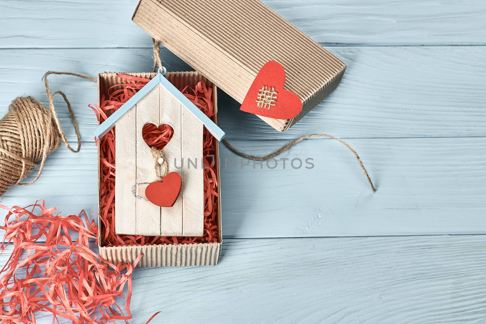 Valentines Day. Love red hearts, souvenir house in gift box, twine. Vintage retro romantic style. Unusual creative greeting card, wooden blue background, copyspace, toned