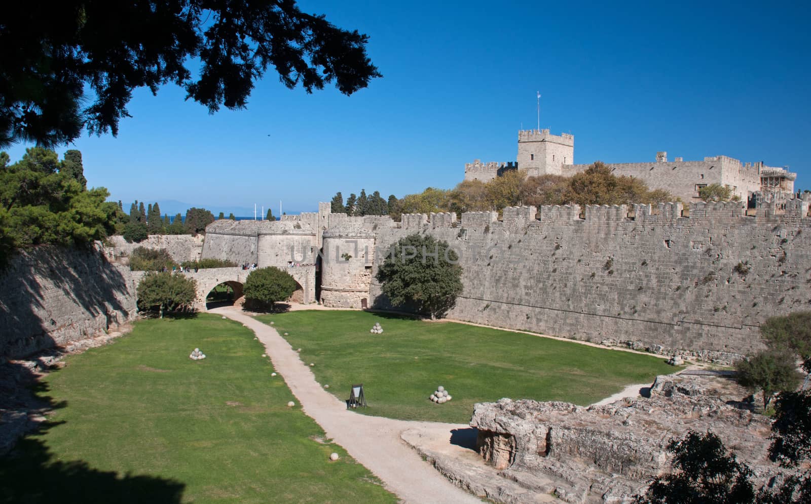 Saint Georges Gate which crosses the dry moats and gives access to Rhodes City. Palace of the Grand Master on horizon.