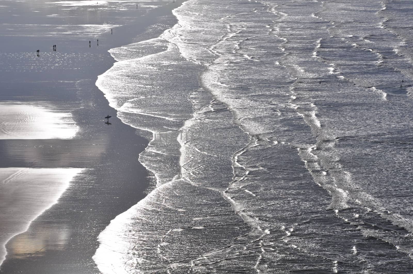 Surfers on the wide expanse of Saunton Sands in North Devon, England