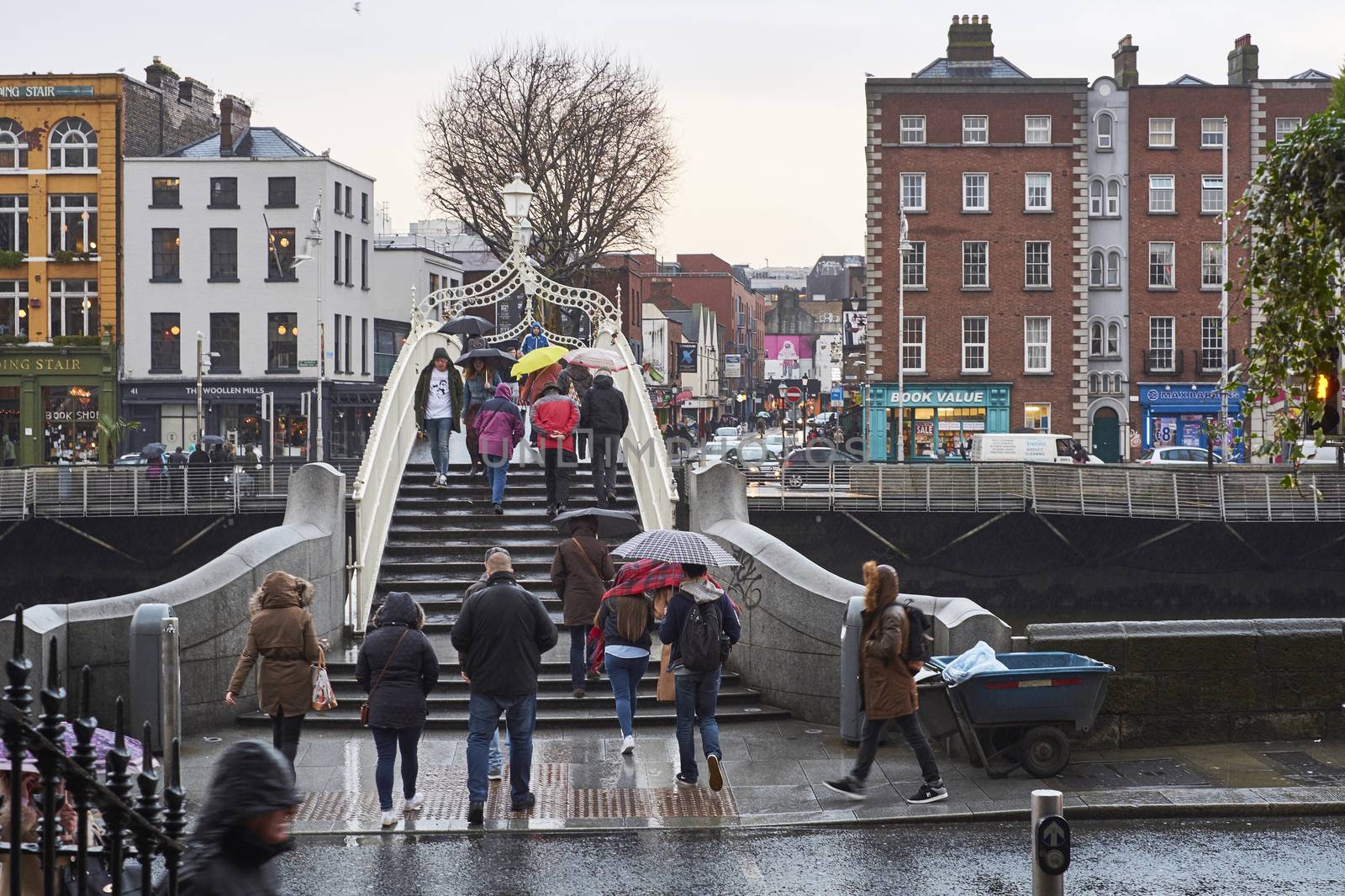 DUBLIN, IRELAND - JANUARY 05: Pedestrians walking over Ha'penny Bridge on a rainy day. The bridge is the main access point to the touristic area of Temple Bar. January 05, 2016 in Dublin