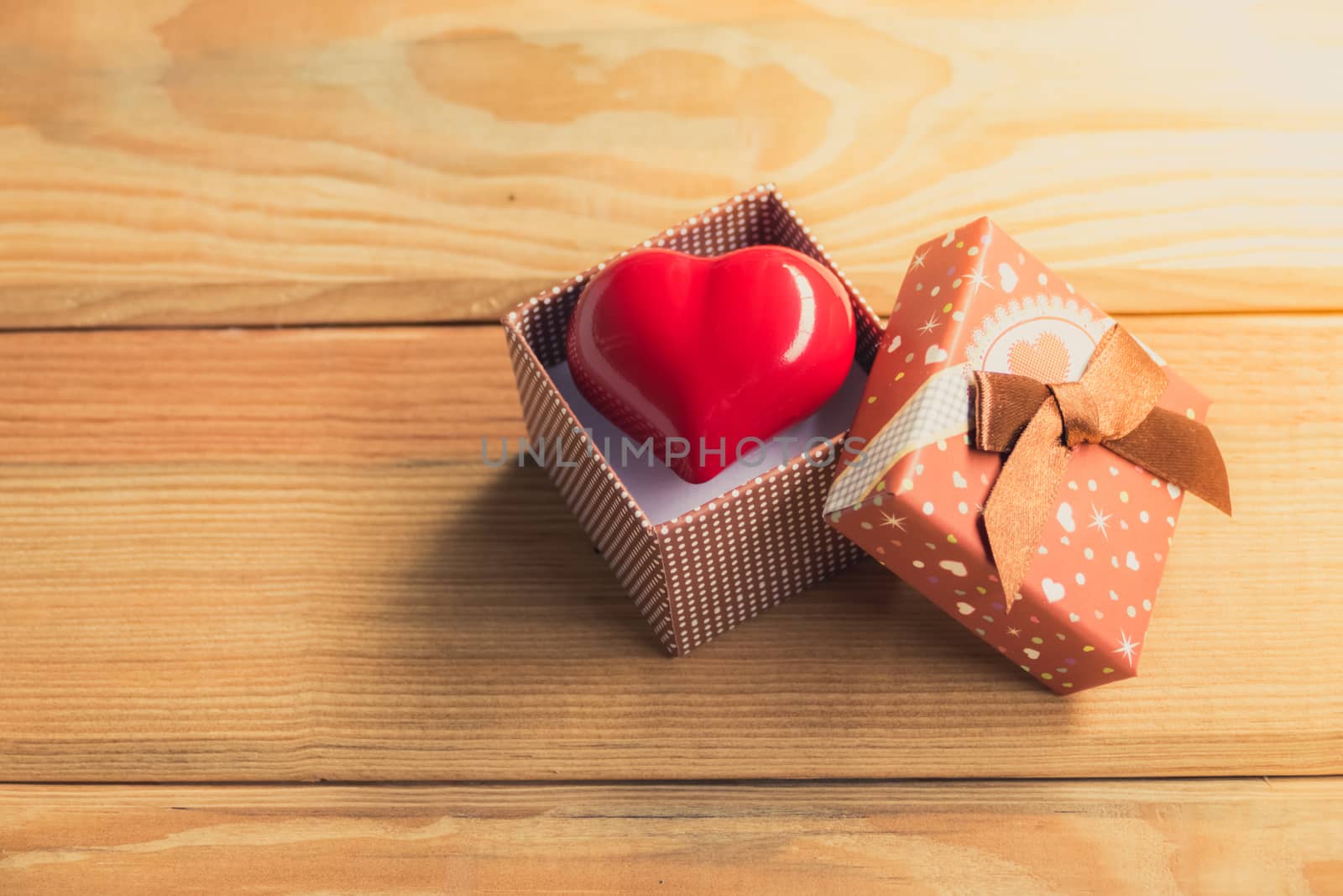 Gift of love. hearty gift. A gift box with a red heart inside. On the wooden floor