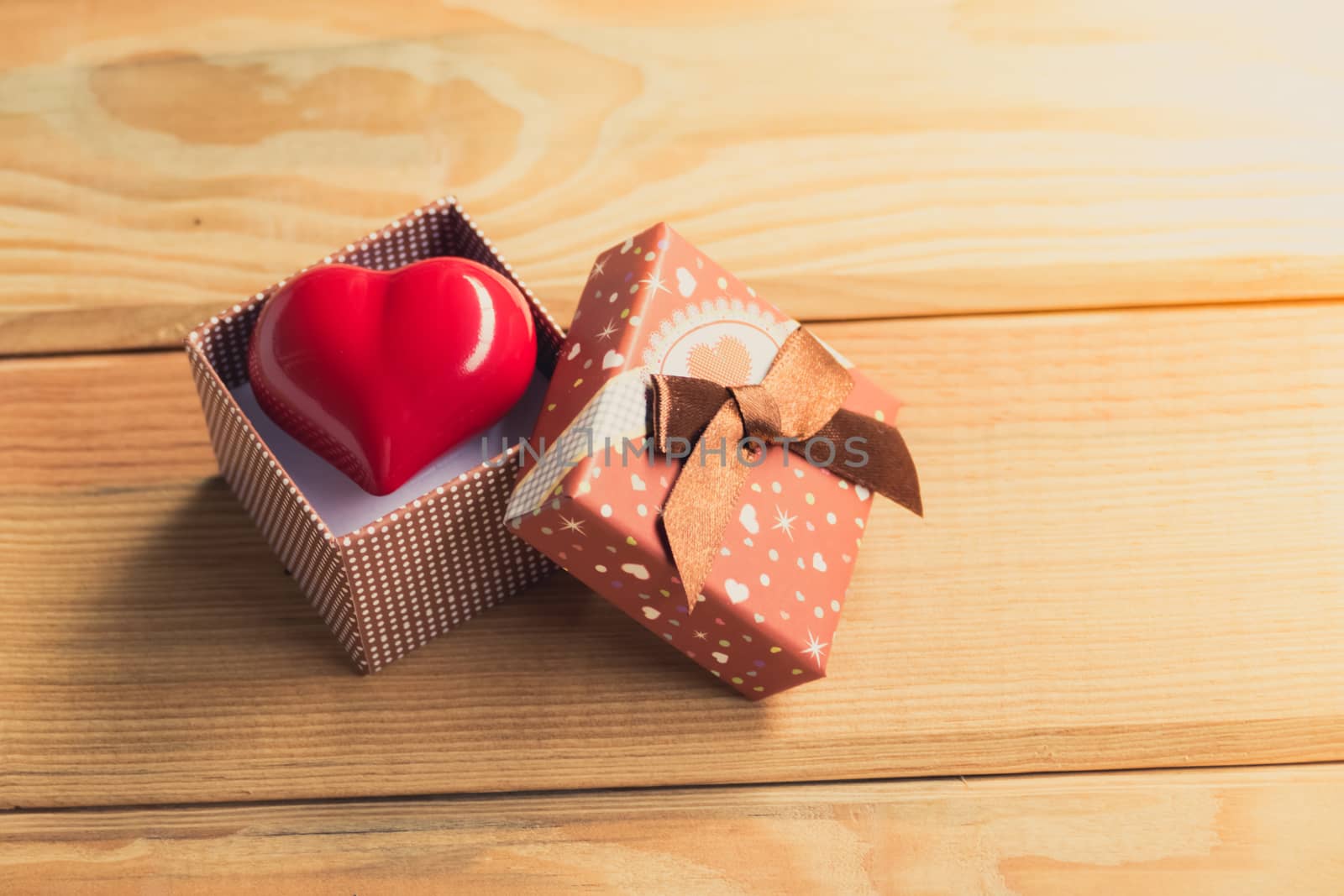 Gift of love. hearty gift. A gift box with a red heart inside. On the wooden floor