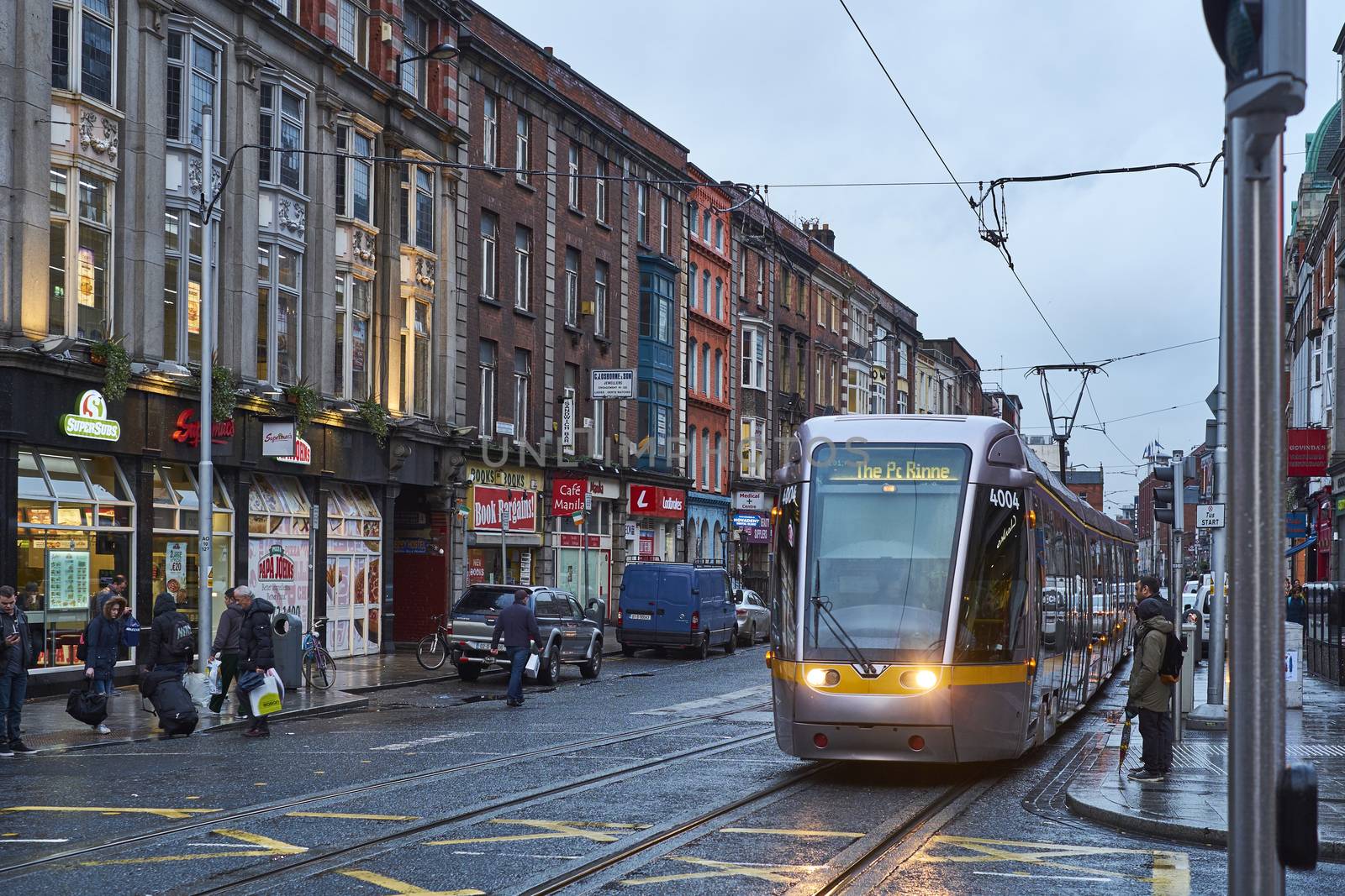 DUBLIN, IRELAND - JANUARY 05: The Luas, Dublin's tram system train, crossing pedestrian area in rainy day. January 05, 2016 in Dublin