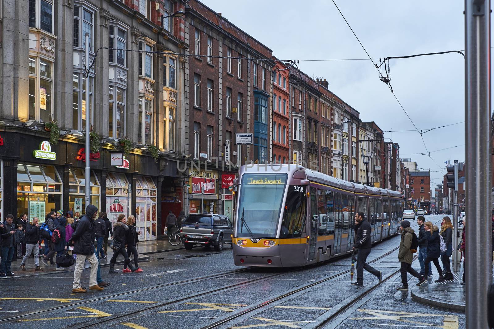 DUBLIN, IRELAND - JANUARY 05: The Luas, Dublin's tram system train, crossing pedestrian area in rainy day. January 05, 2016 in Dublin
