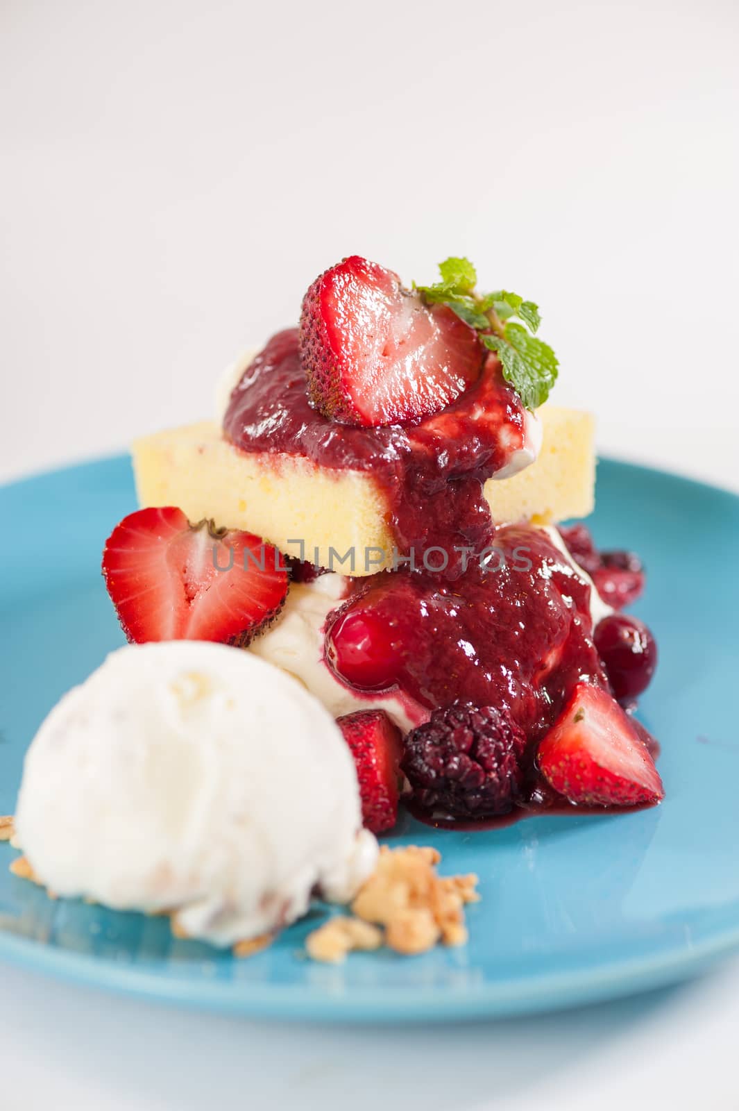 Yellow cake and vanilla ice cream dressed with strawberry sauce on blue dish