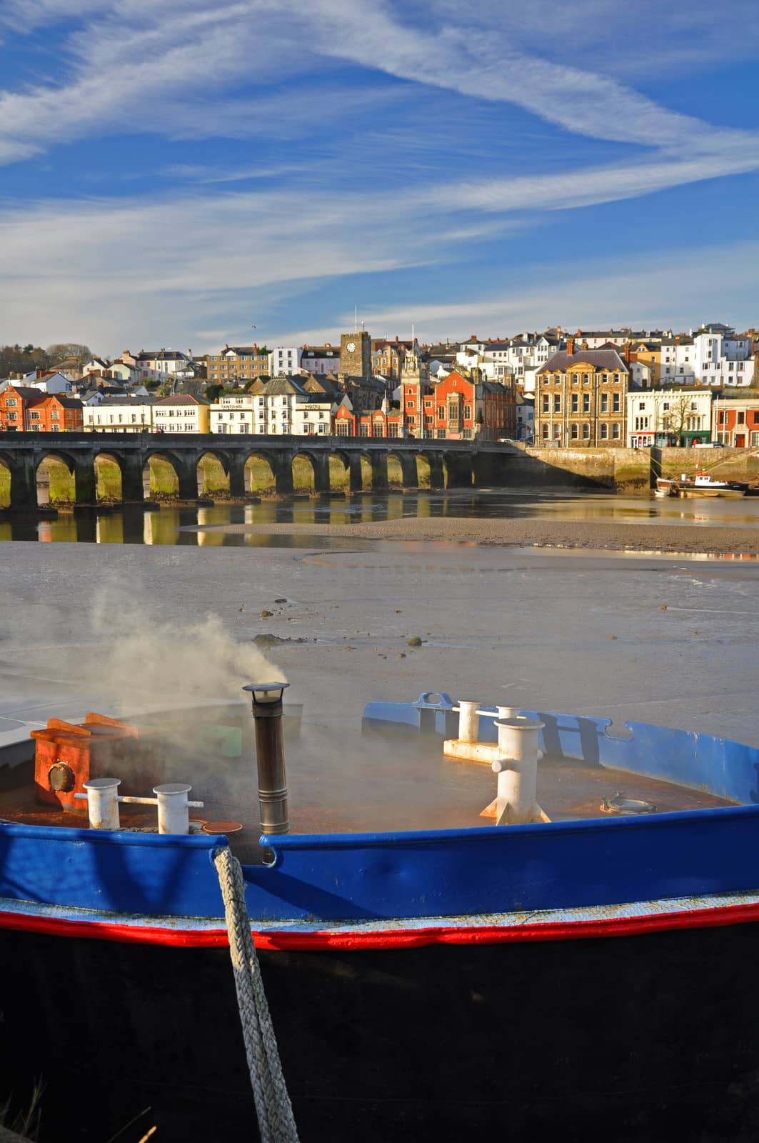 An old boat berthed at Wooda Wharfe, on the River Torridge. The old bridge which crosses the River Torridge is shown together with the ancient port of Bideford. Bideford is in North Devon, England