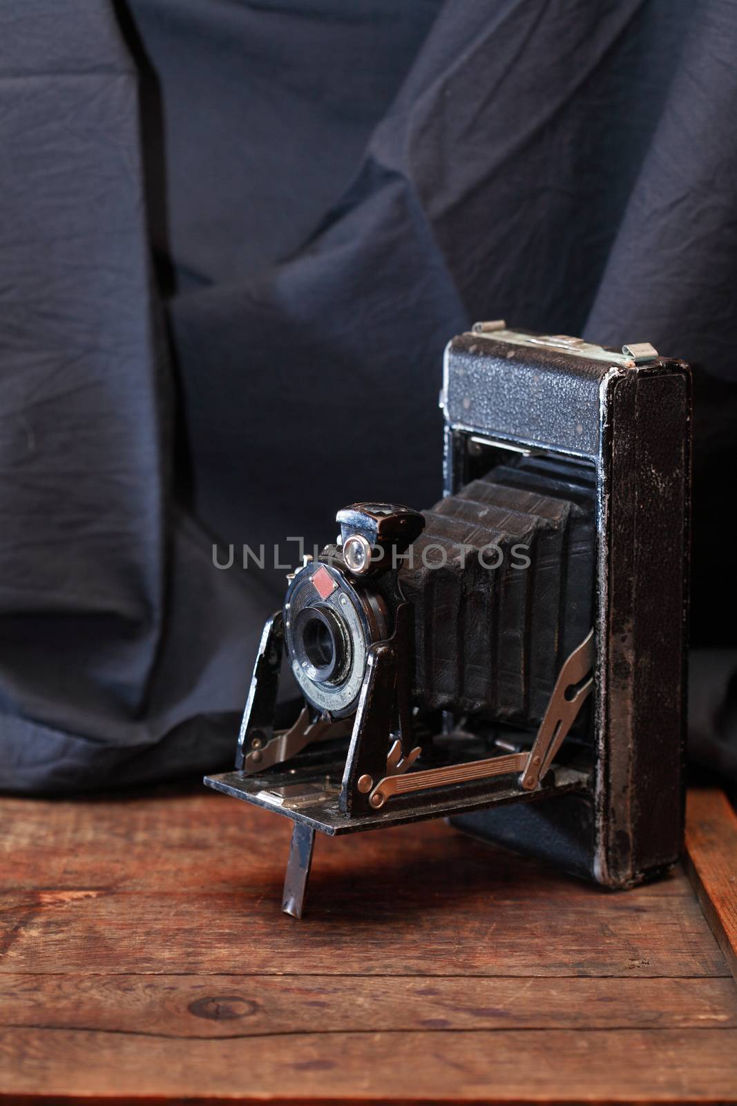 Closeup of old film camera on nice wooden background against textile