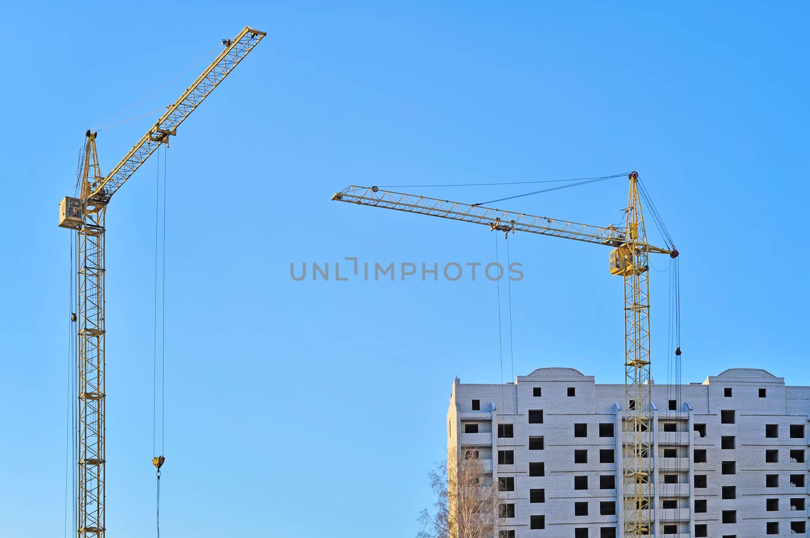 Cranes and building construction on the background of blue sky